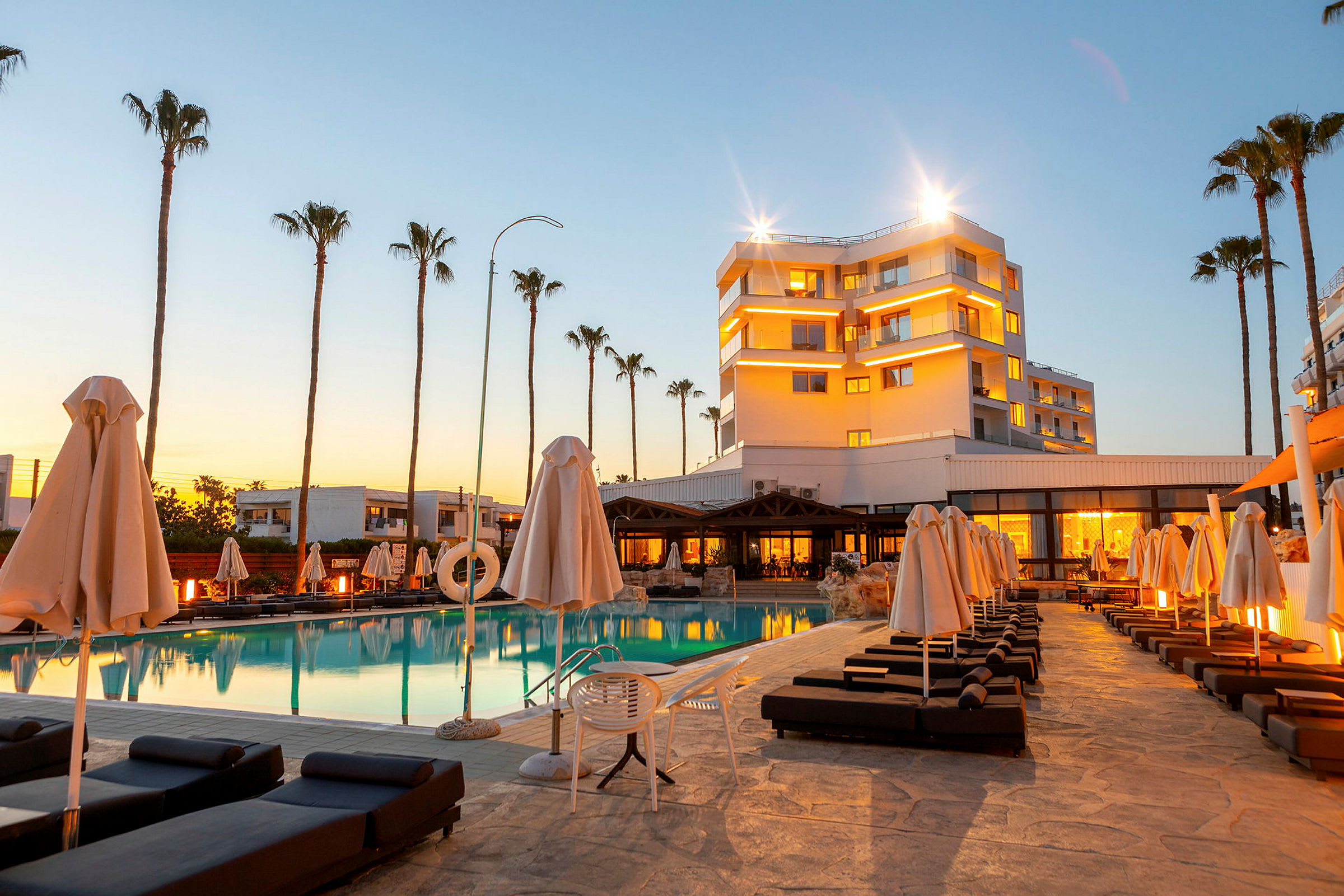 Hotell vid en pool med solstolar och parasoller. (AI-genererad text)