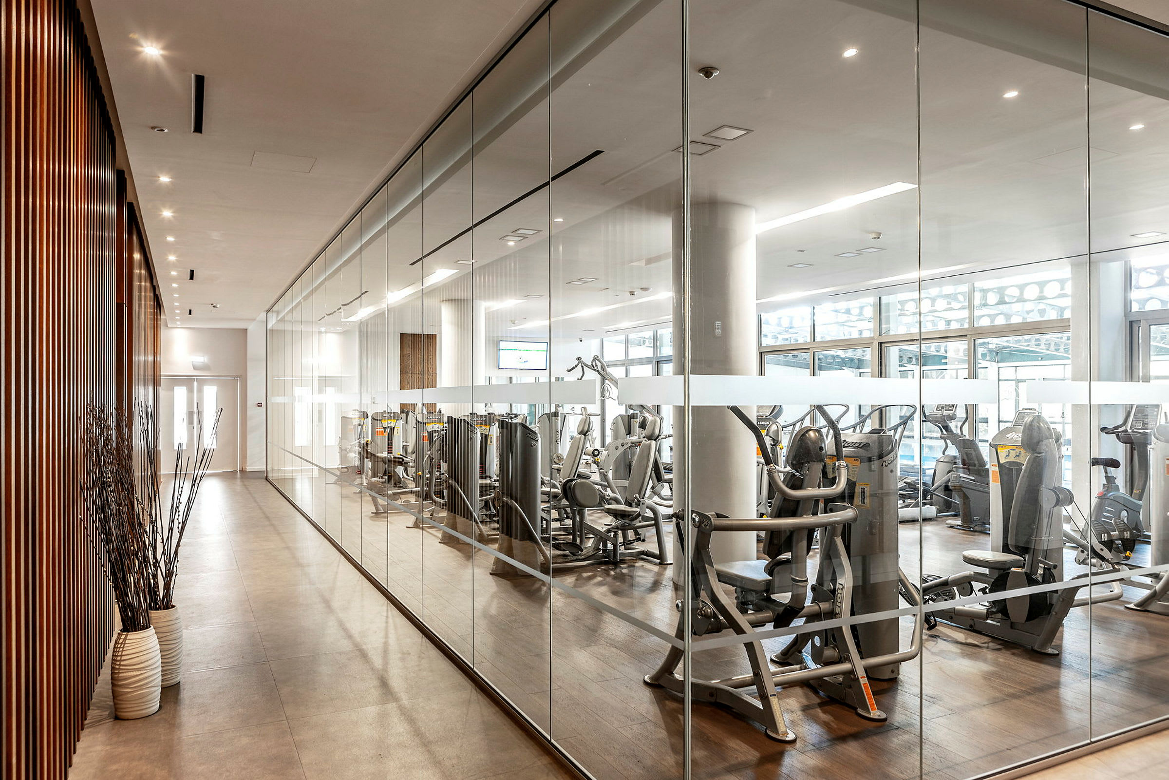 Modernt gym med träningsmaskiner bakom glasvägg. (AI-genererad text)