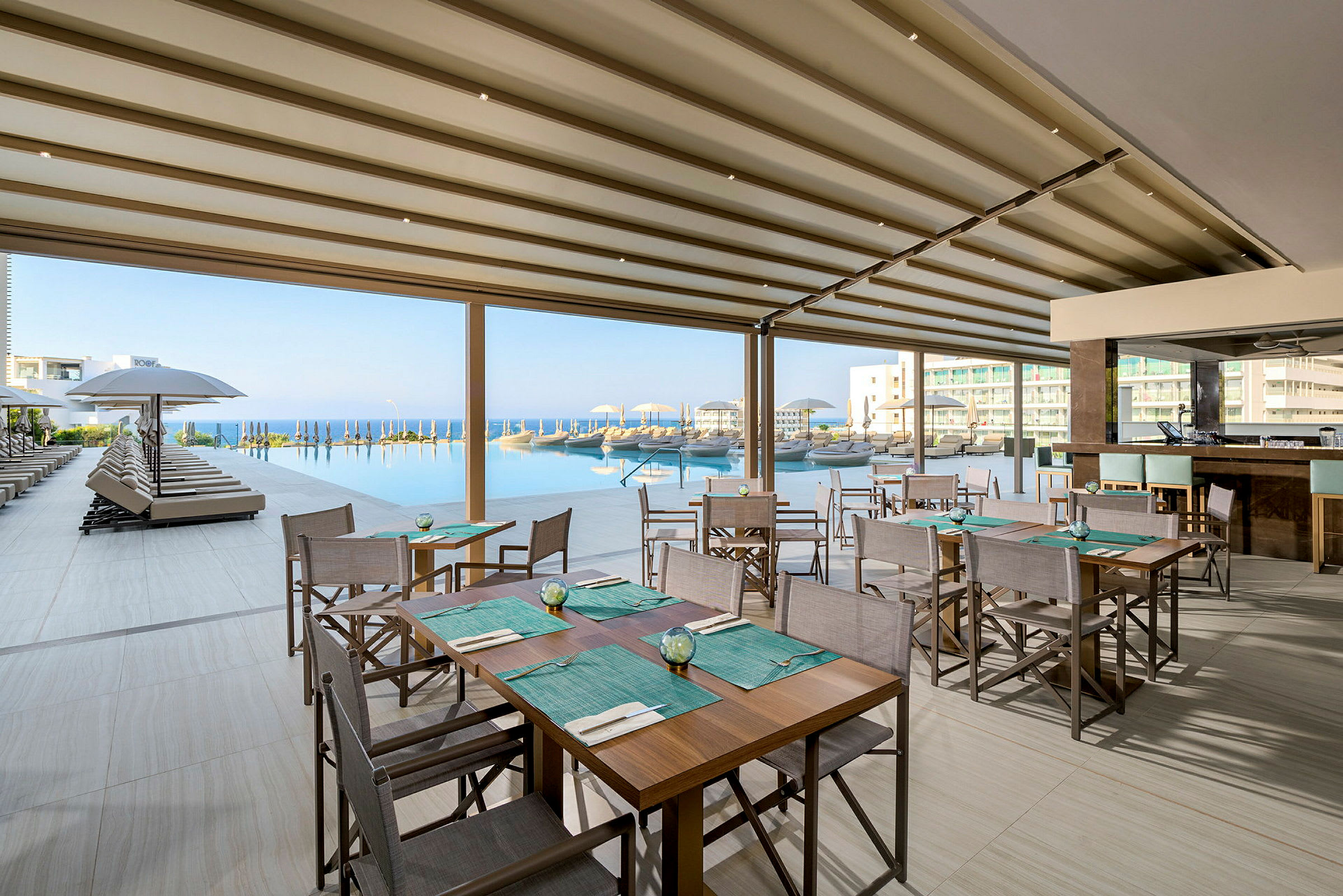 Restaurang med sittplatser vid en pool med utsikt över havet. (AI-genererad text)