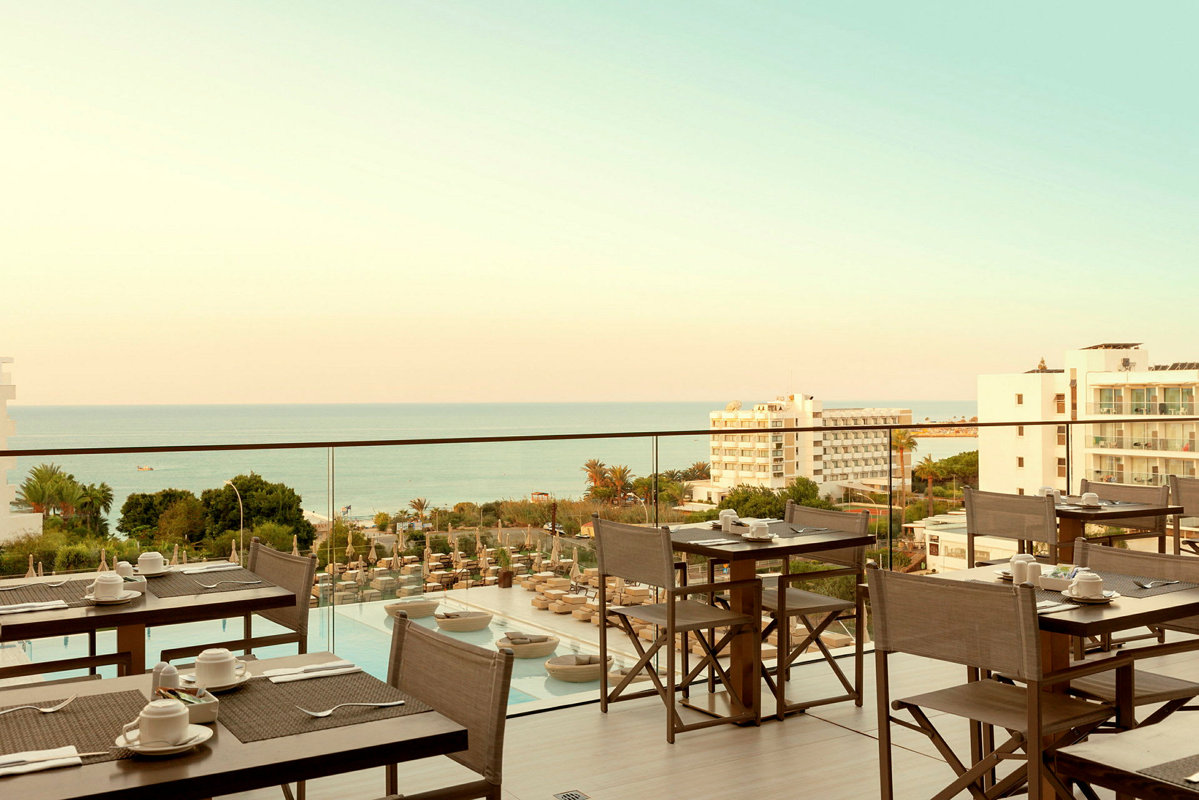 Restaurangterrass med utsikt över havet och omgivande byggnader. (AI-genererad text)
