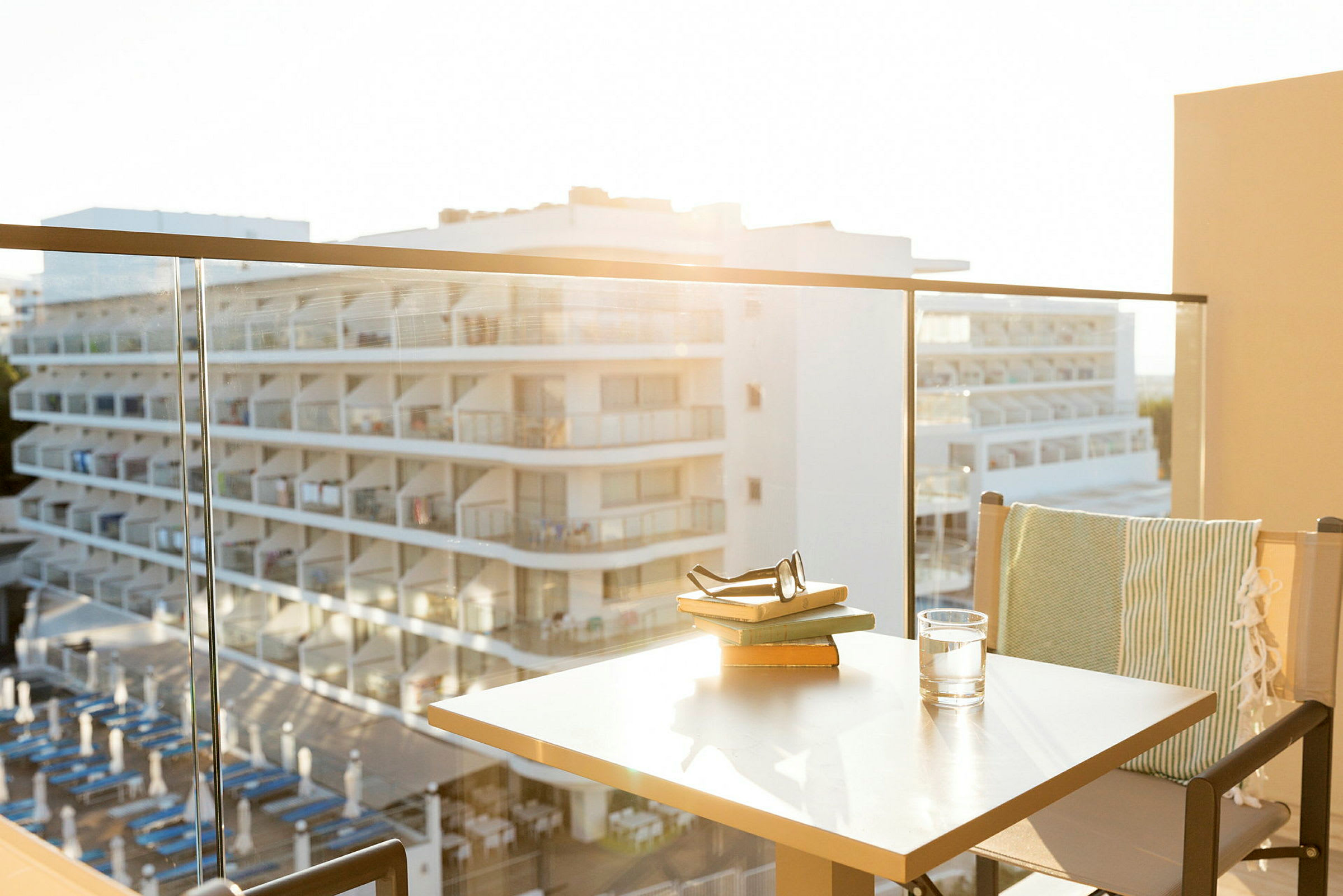 Utsikt från en balkong med glasräcke mot ett hotell med balkonger. (AI-genererad text)