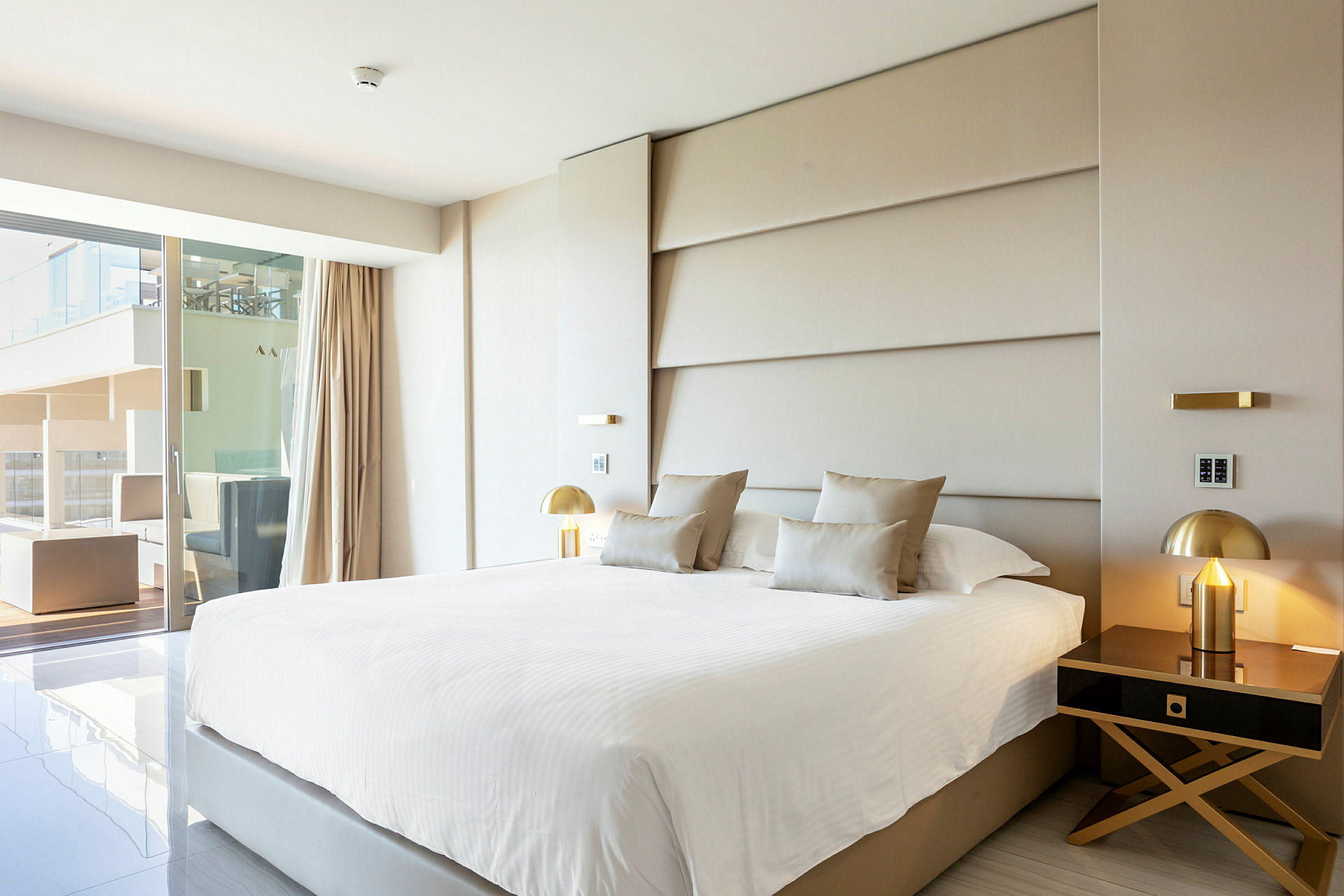 Modernt hotellrum med stor säng, elegant inredning och utsikt mot en terrass. (AI-genererad text)
