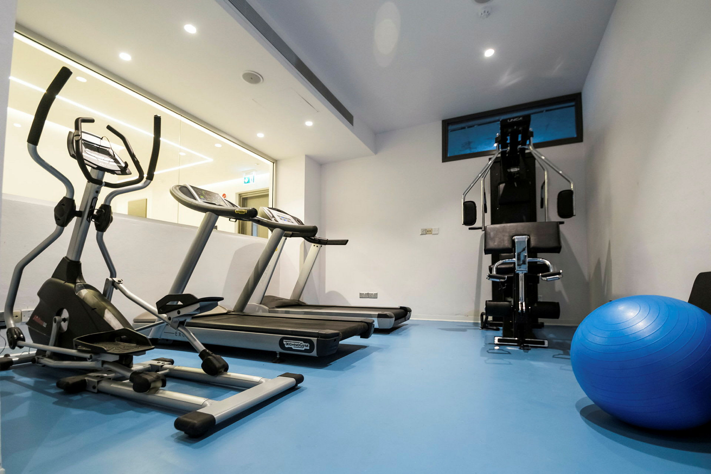 Ett gymrum med träningsmaskiner och en blå pilatesboll. (AI-genererad text)