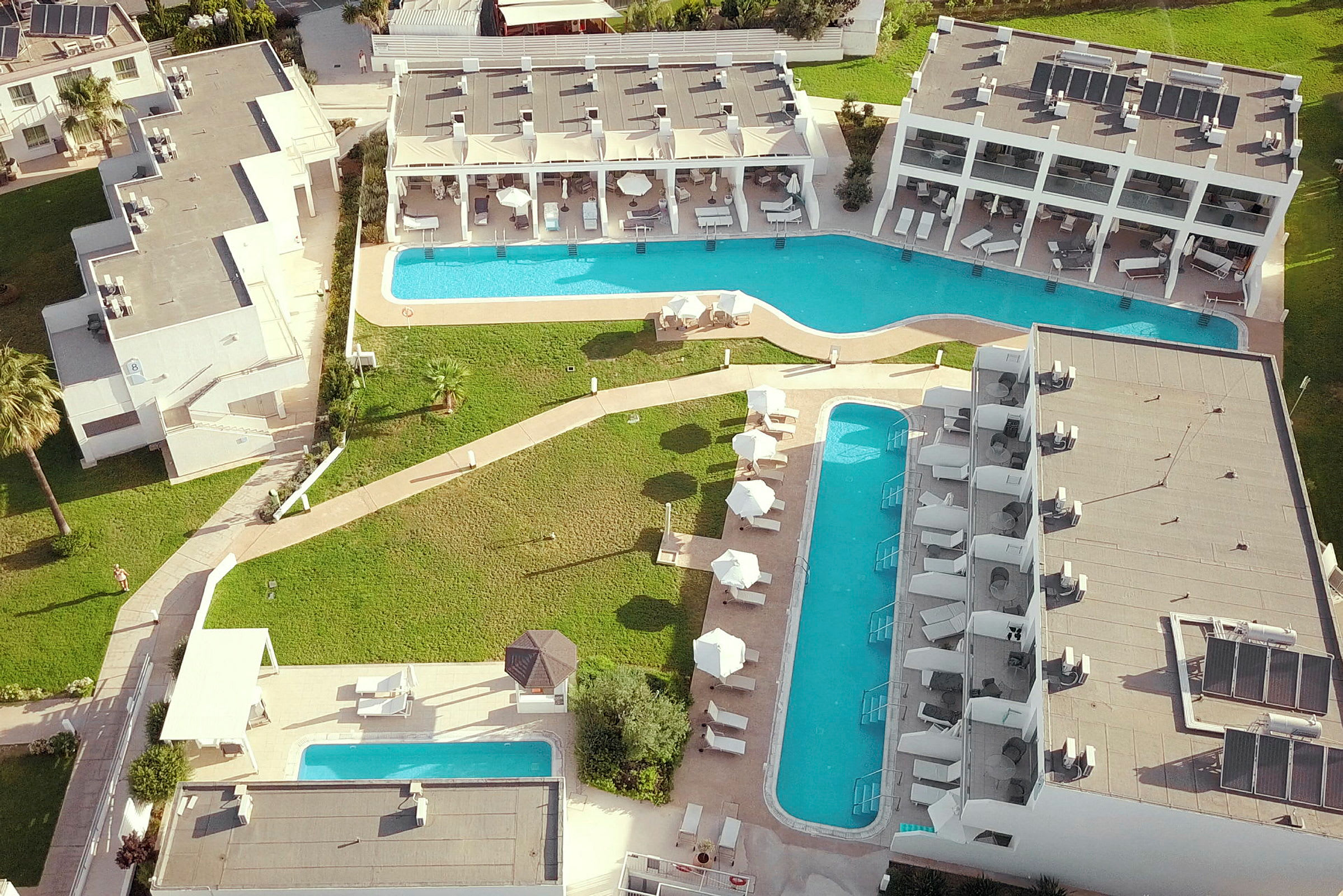 Flygfoto av hotell med poolområden och grönområden. (AI-genererad text)