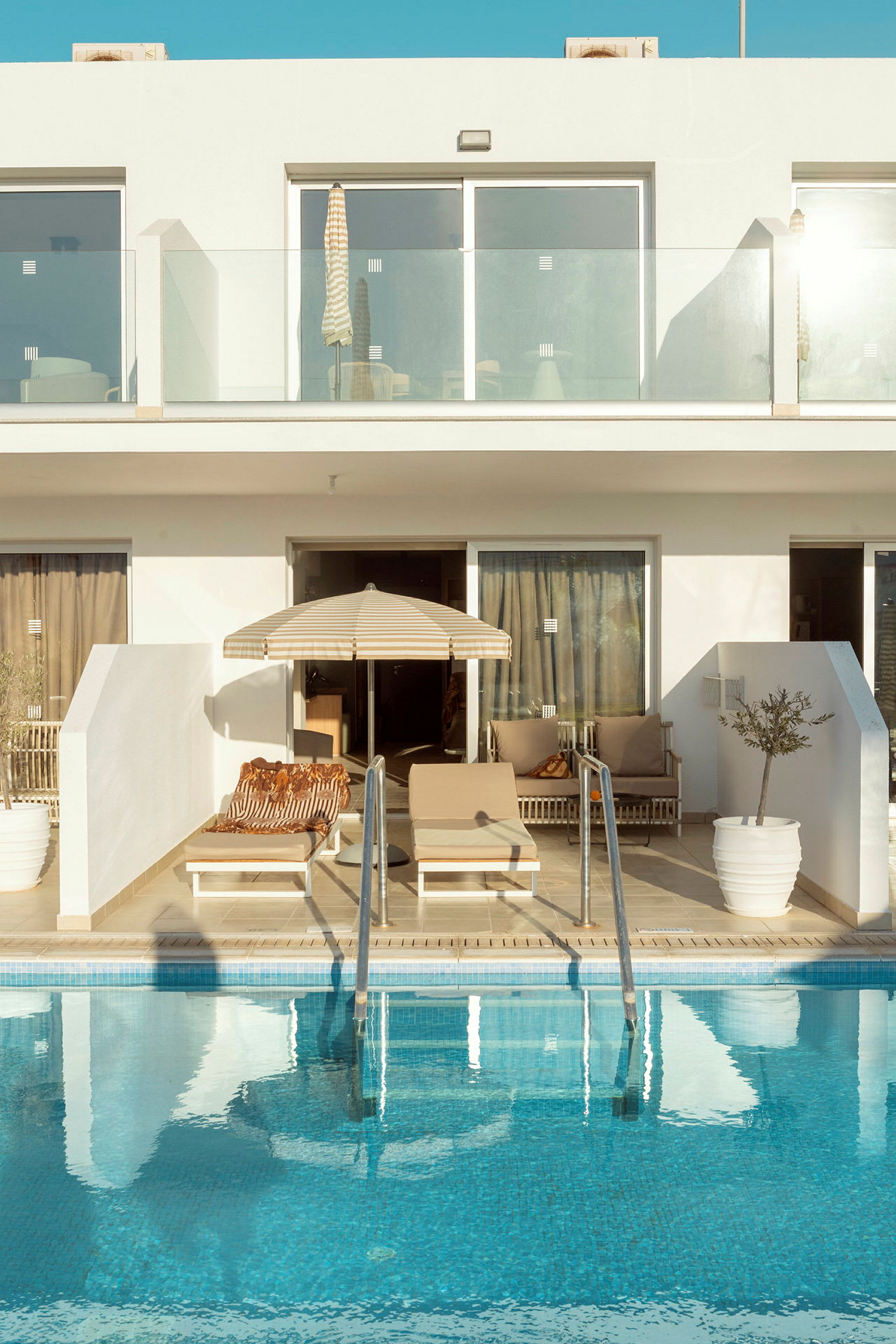 Bild av en modern semestervilla med privata solstolar, parasoll och pool. (AI-genererad text)
