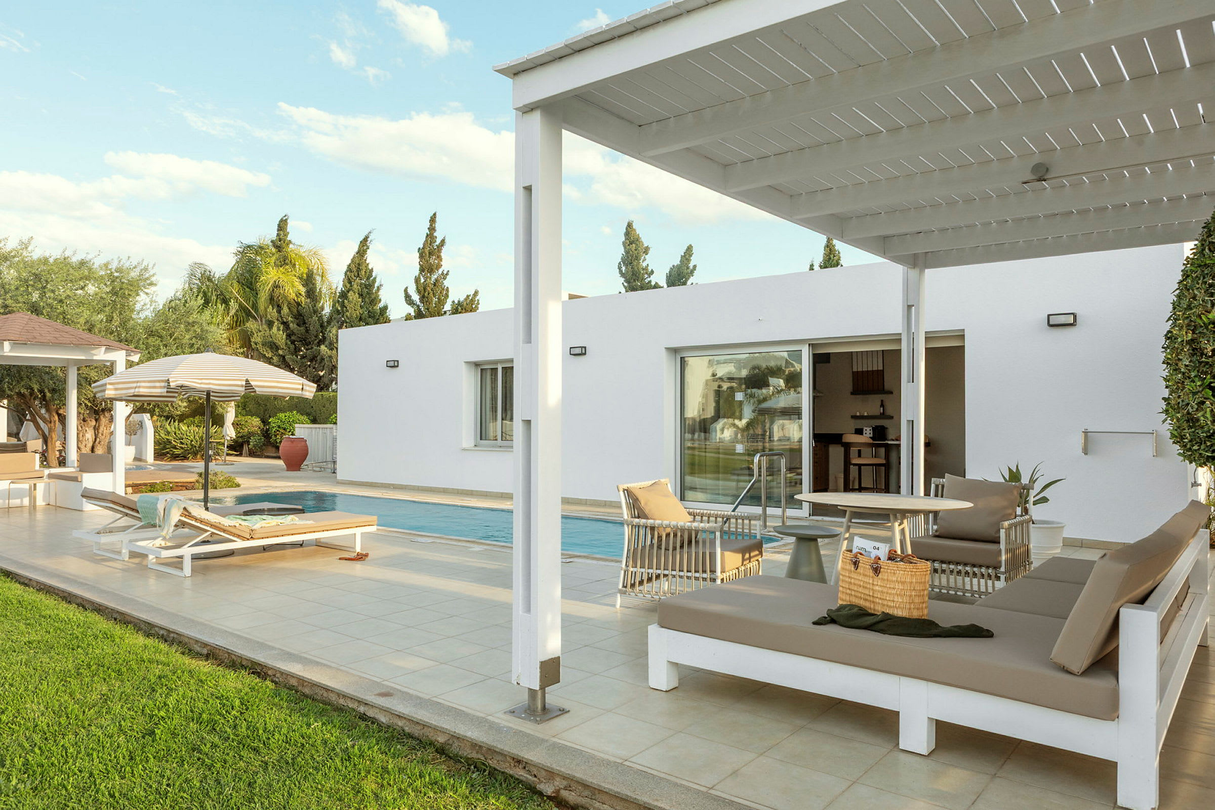 Utomhusområde med en pool, solstolar och en pergola vid sidan av en modern byggnad. (AI-genererad text)