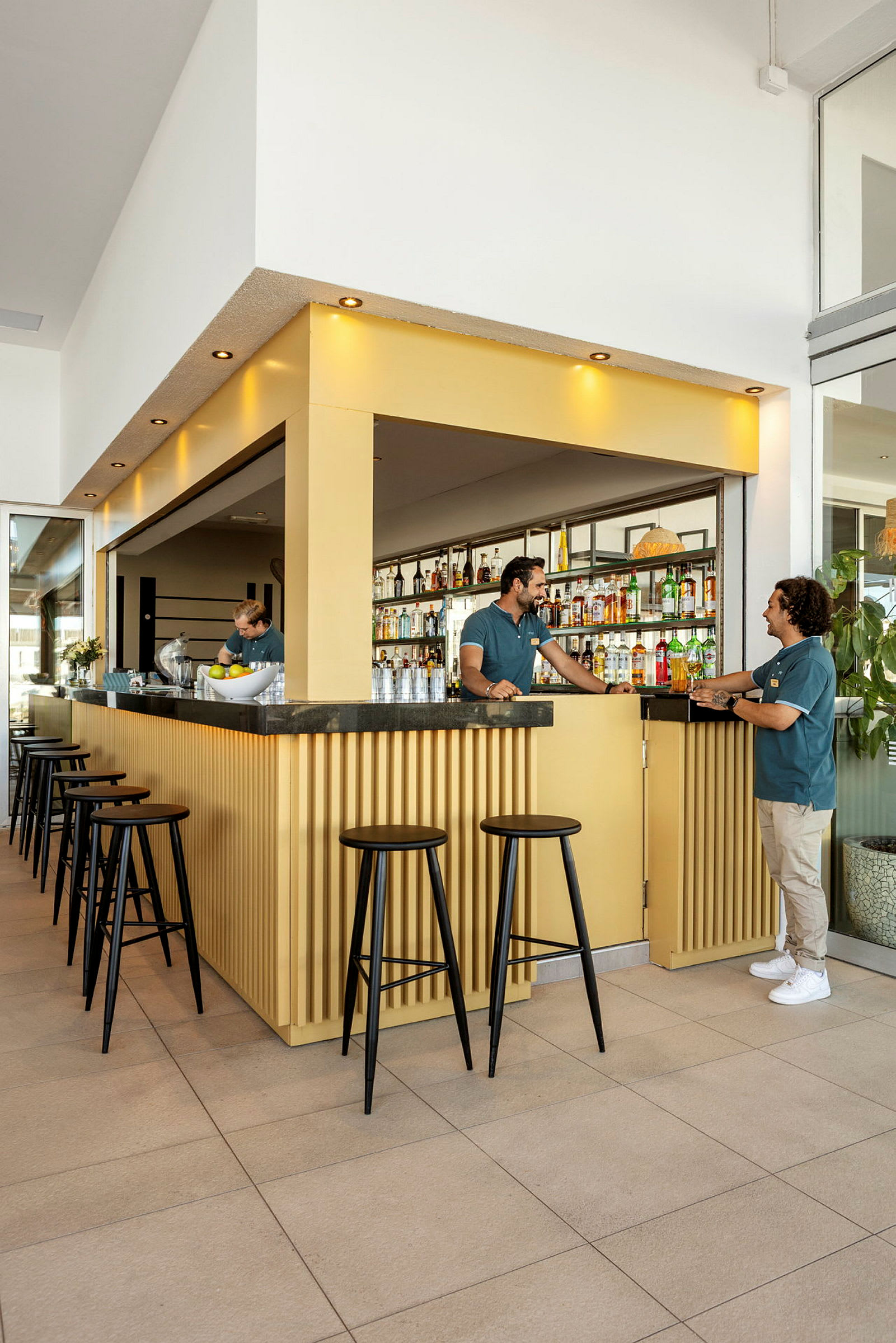 En modern bar med gul inredning och svarta höga stolar. (AI-genererad text)