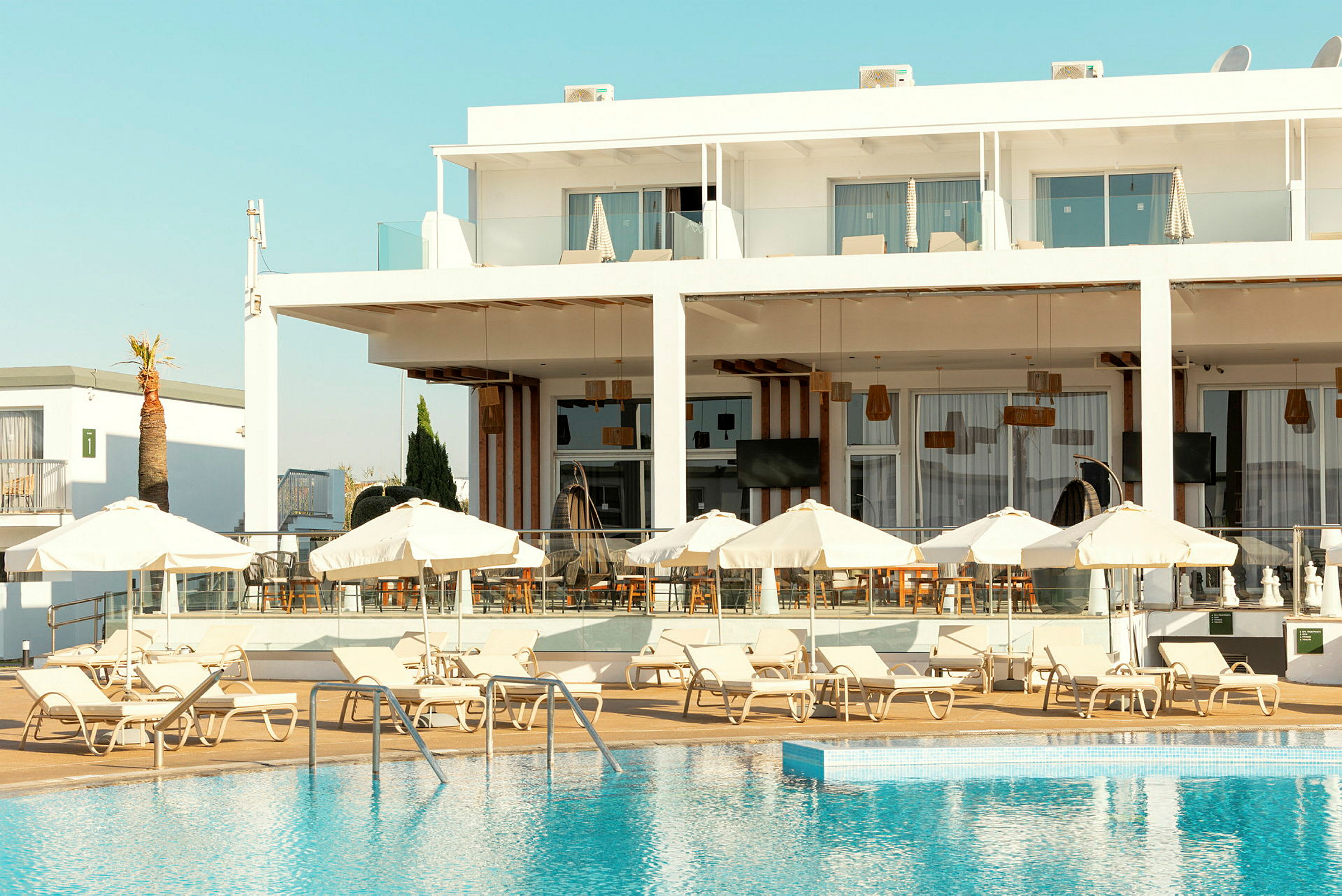 Bild av ett hotell med solstolar och parasoller vid en pool. (AI-genererad text)