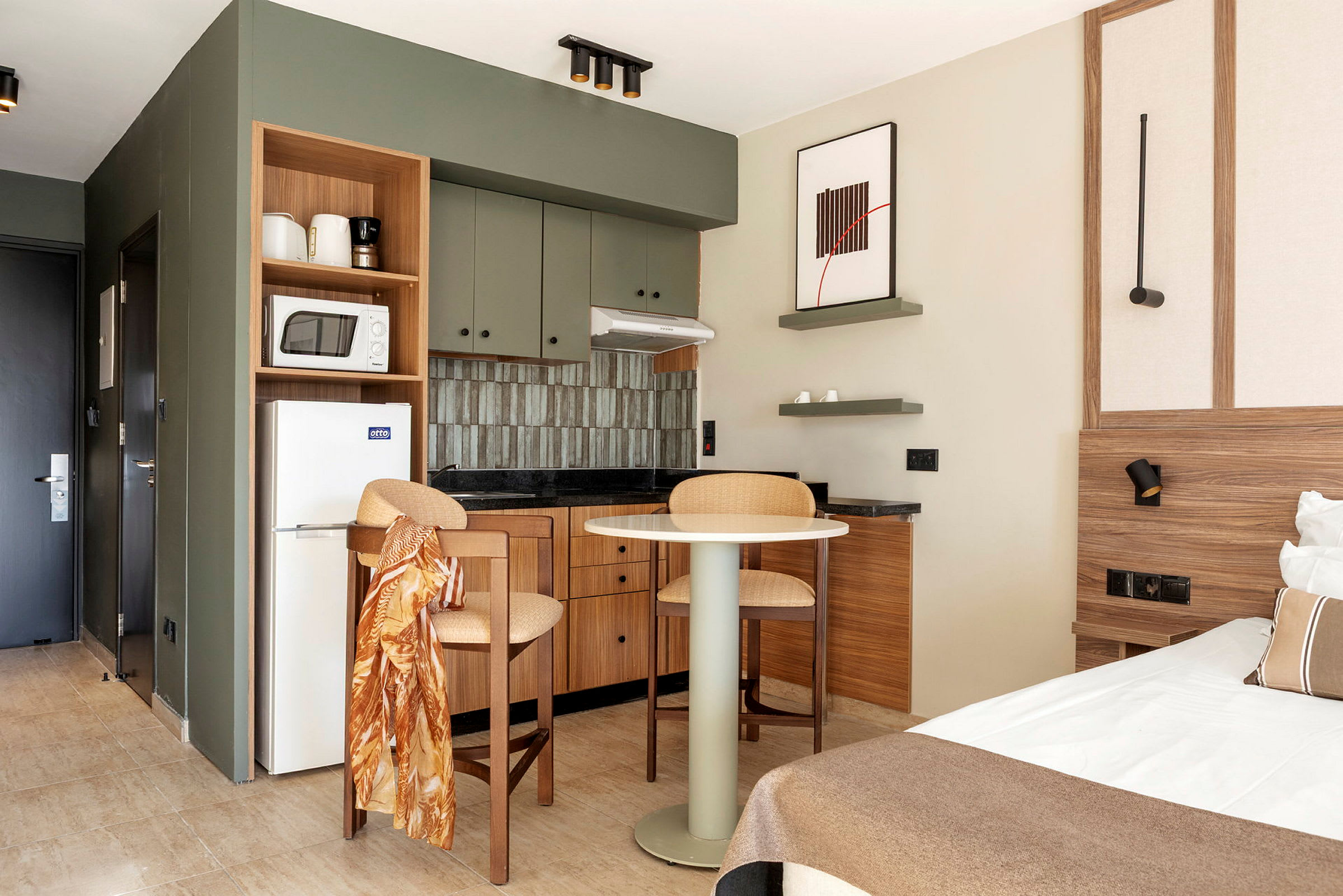 Inredning av ett hotellrum med köksdel och en dubbelsäng. (AI-genererad text)