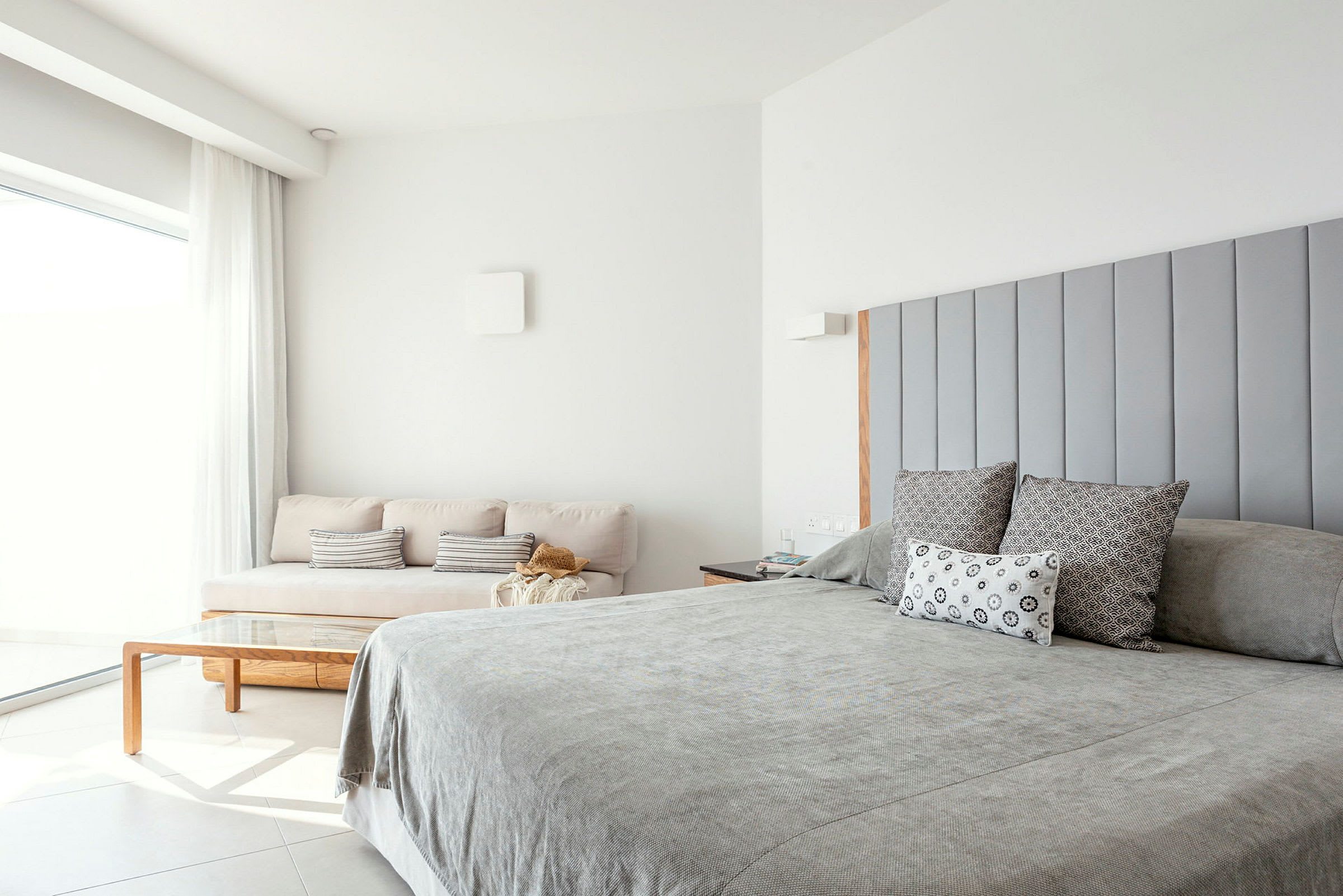 Ett ljus och modernt sovrum med en dubbelsäng och en soffa. (AI-genererad text)