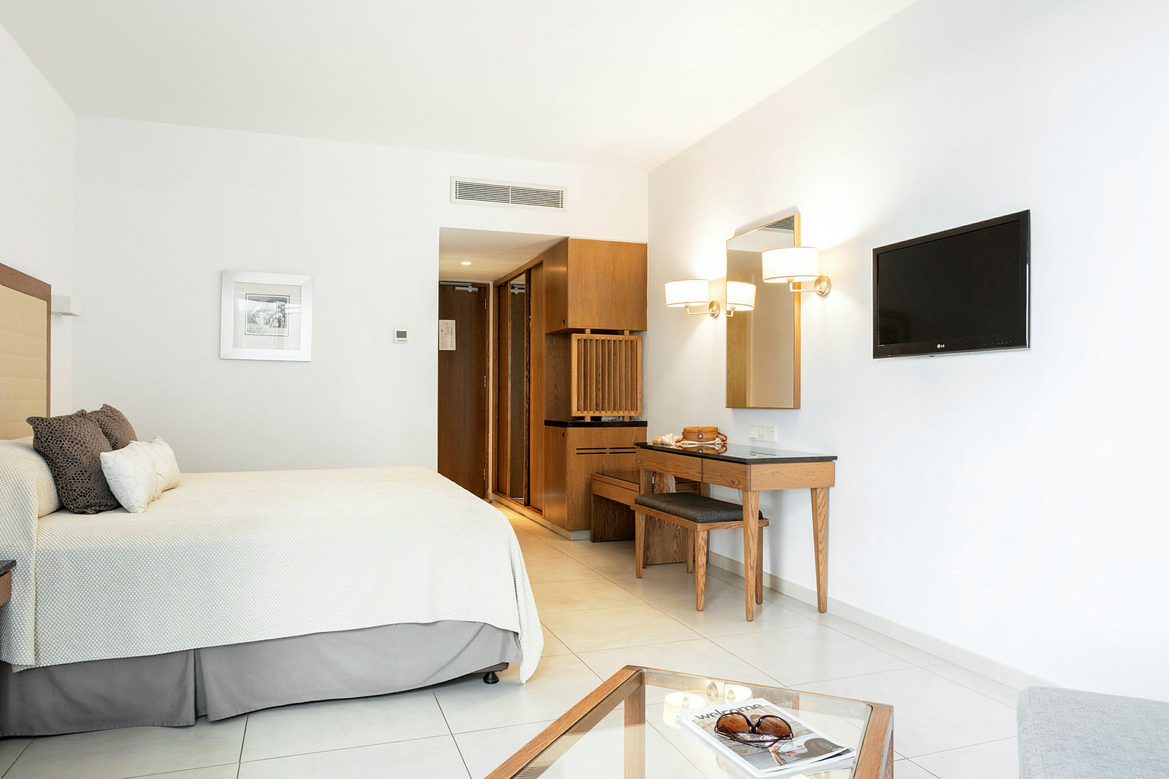 En minimalistisk hotellrum med säng, vägg-TV och skrivbord. (AI-genererad text)