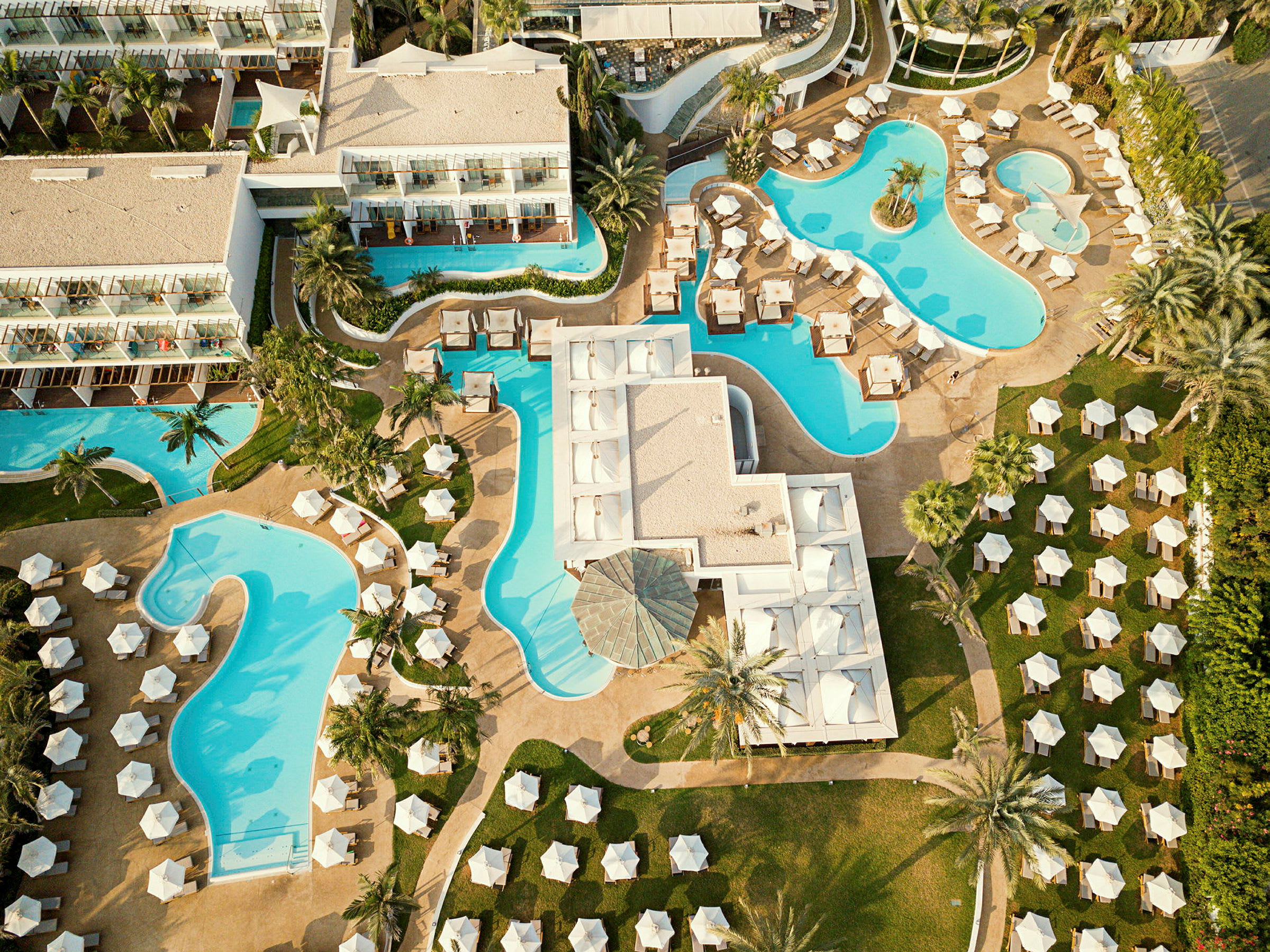 Flygfoto över hotell med flera pooler och solstolar. (AI-genererad text)