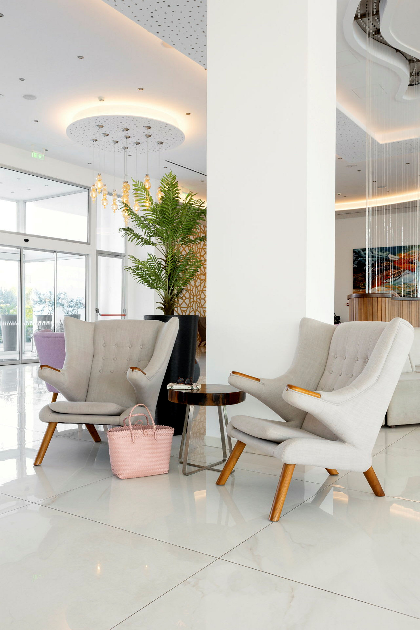 Två ljusa fåtöljer och ett sidobord i ett modernt hotellobbyområde. (AI-genererad text)