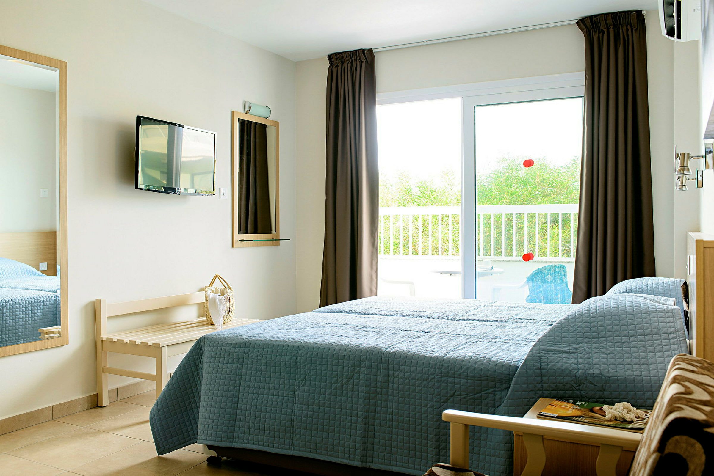 Ett hotellrum med en säng bredvid en glasdörr som leder till en balkong. (AI-genererad text)