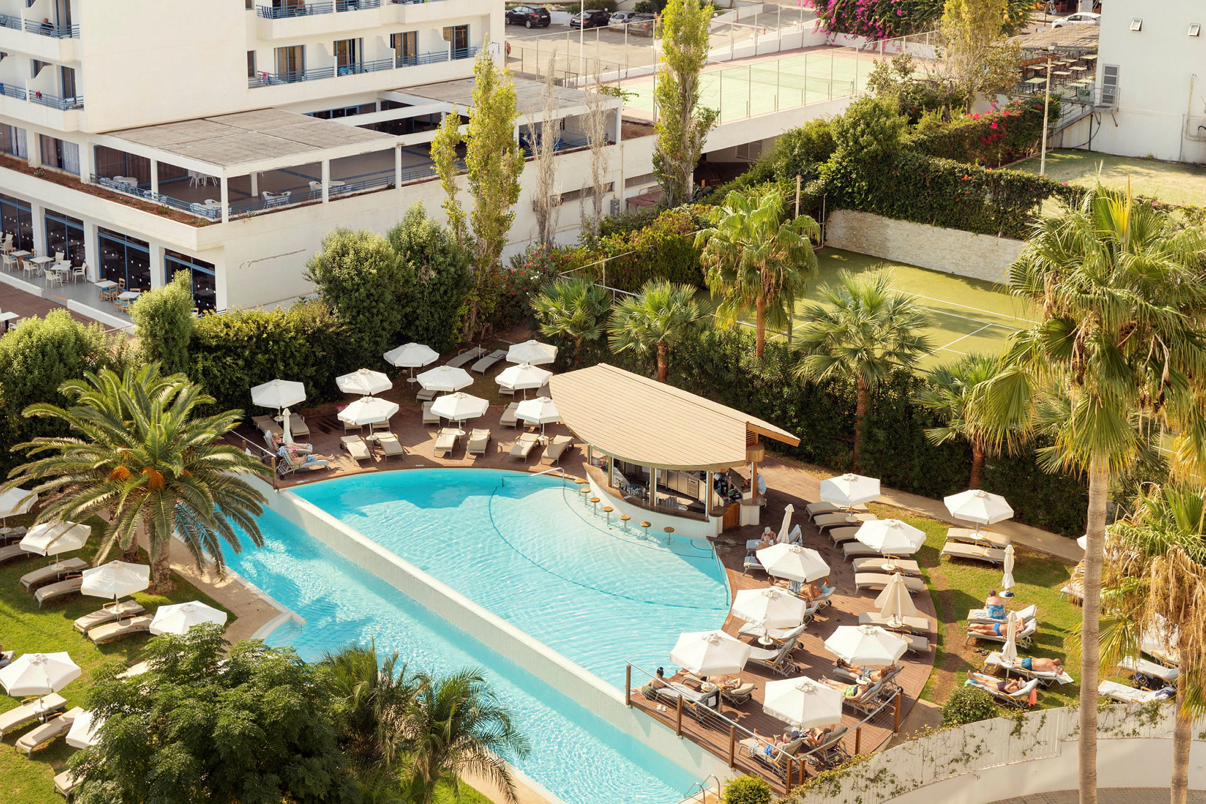 Bild av hotellpoolområde med solstolar, parasoller, palmer och servering. (AI-genererad text)