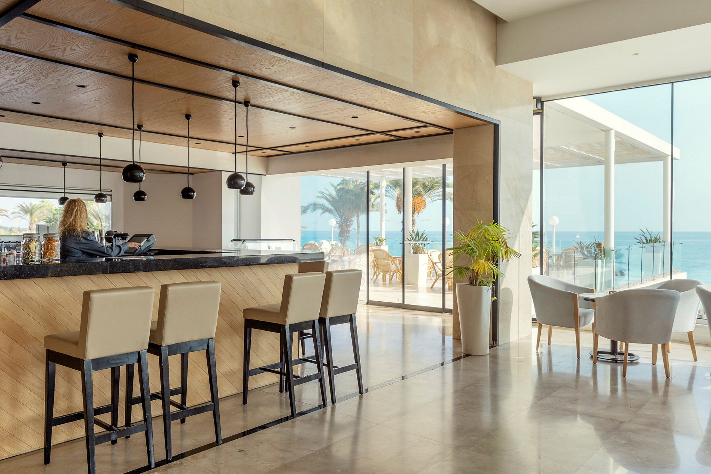 Hotellbar med höga stolar och utsikt mot havet. (AI-genererad text)