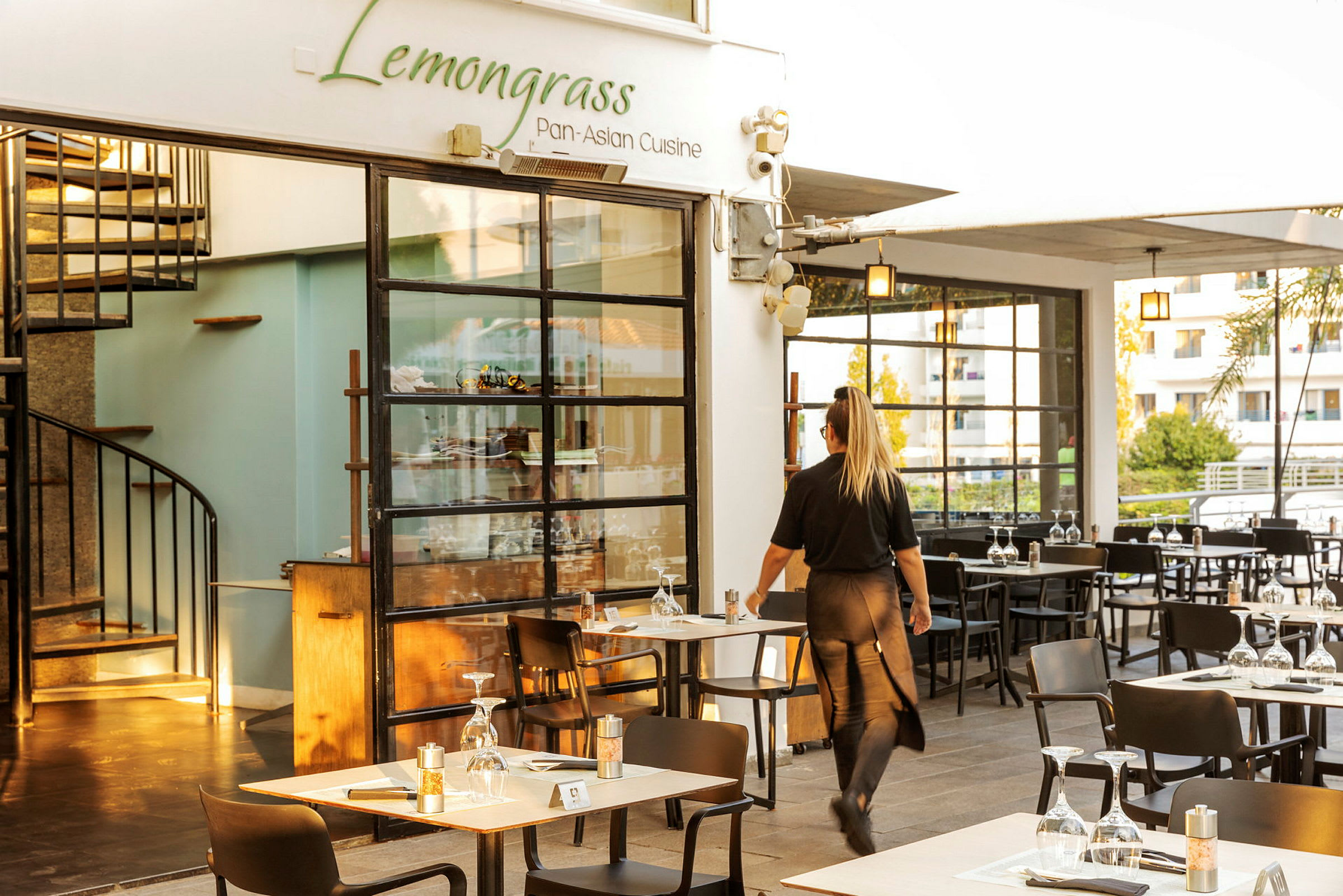 Restaurang med namnet Lemongrass och en servitör som går mellan borden. (AI-genererad text)