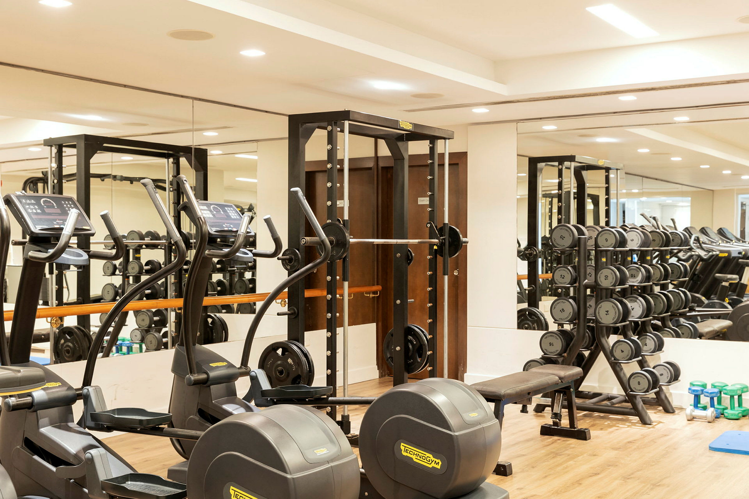 Gym med träningsmaskiner, fria vikter och spegelvägg. (AI-genererad text)
