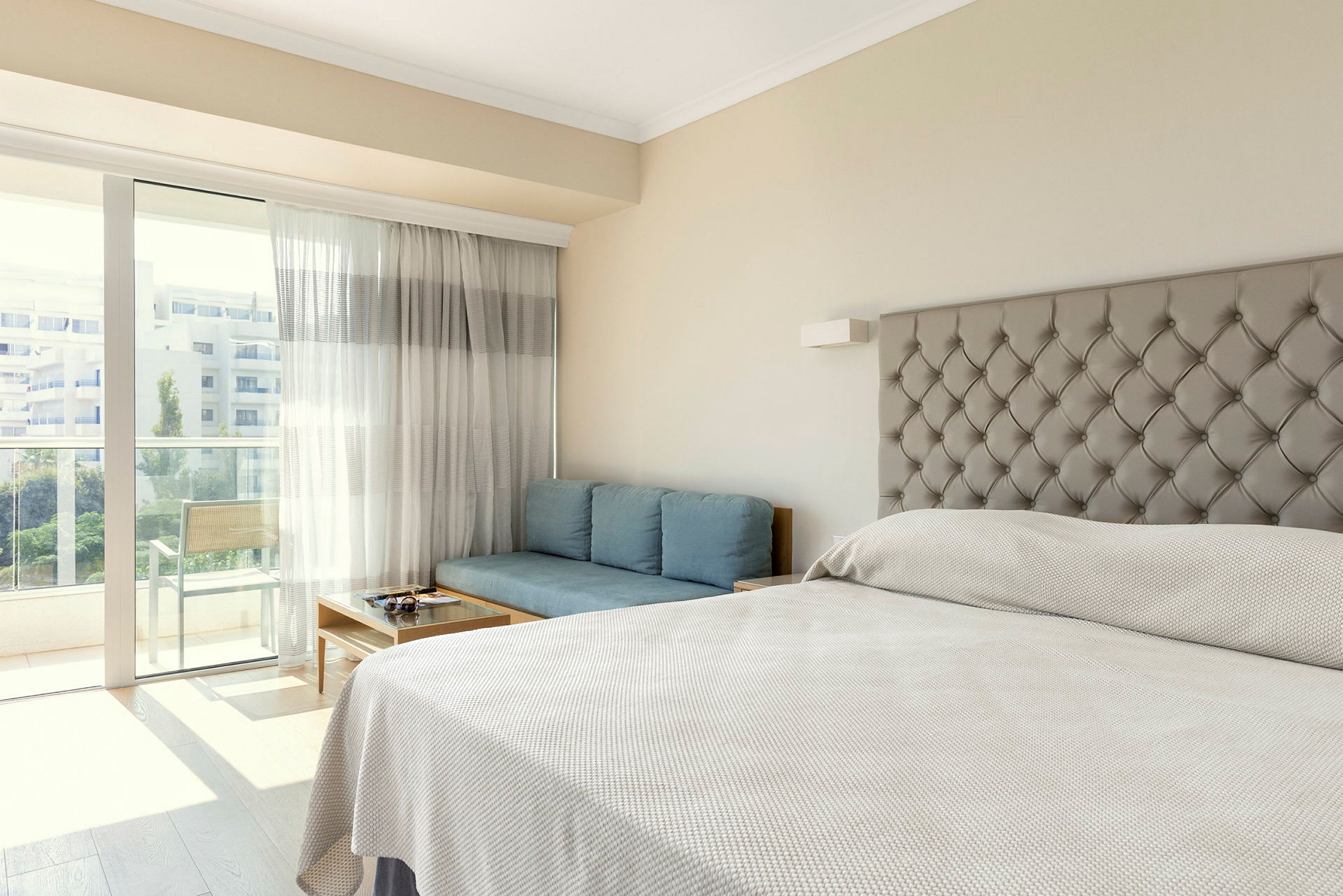 Ett hotellrum med en säng, en blå soffa och en balkong. (AI-genererad text)