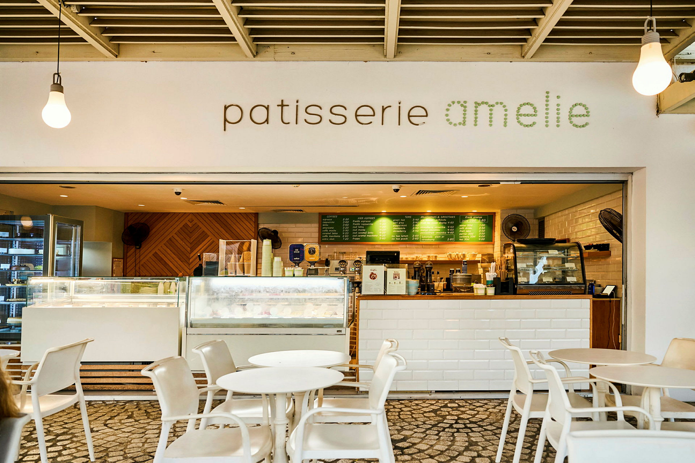 Ett kafé med skylt "patisserie amelie" och en inbjudande serveringsdisk med bord och stolar framför. (AI-genererad text)
