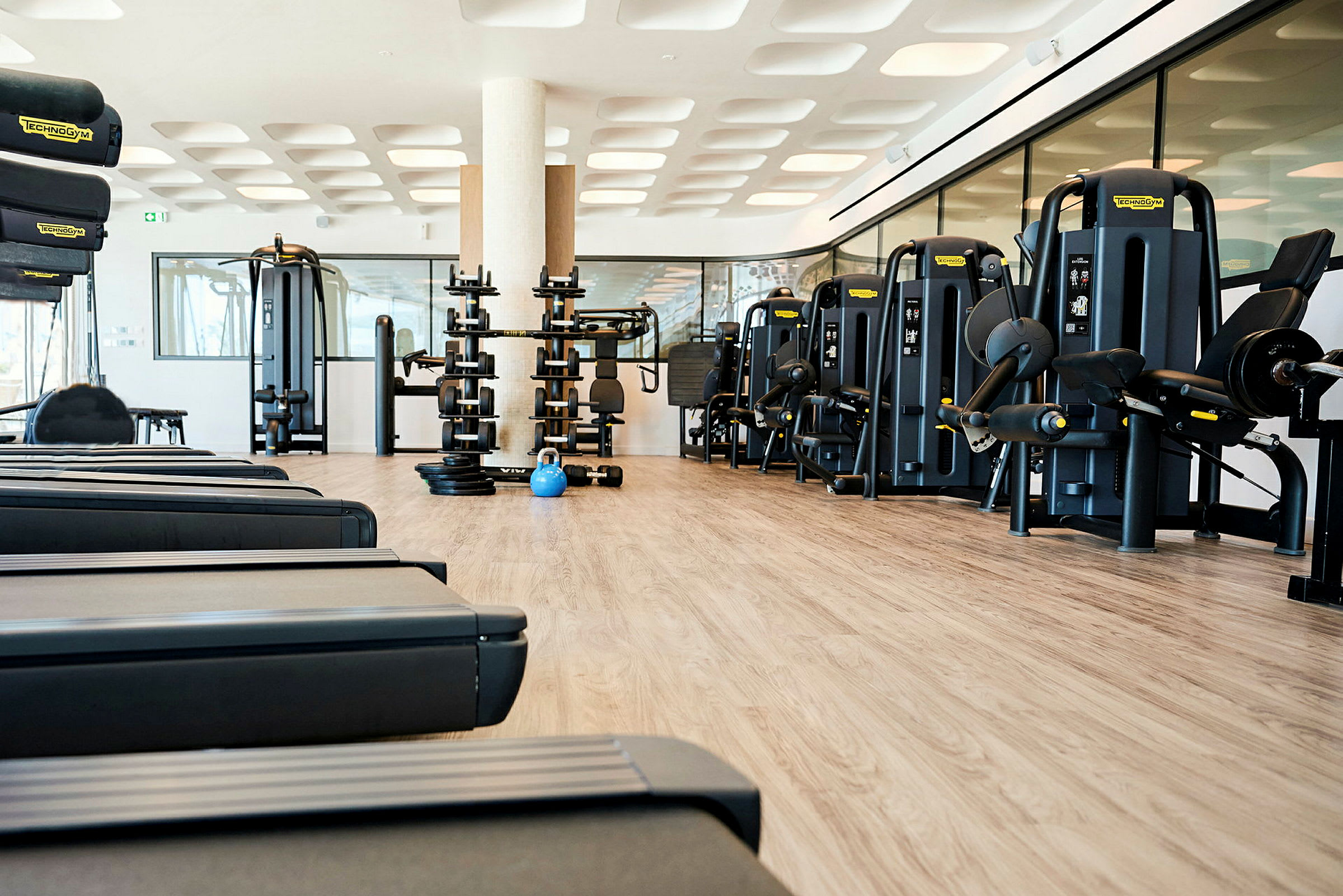 En gymmiljö med olika träningsmaskiner och vikter på ett trägolv. (AI-genererad text)