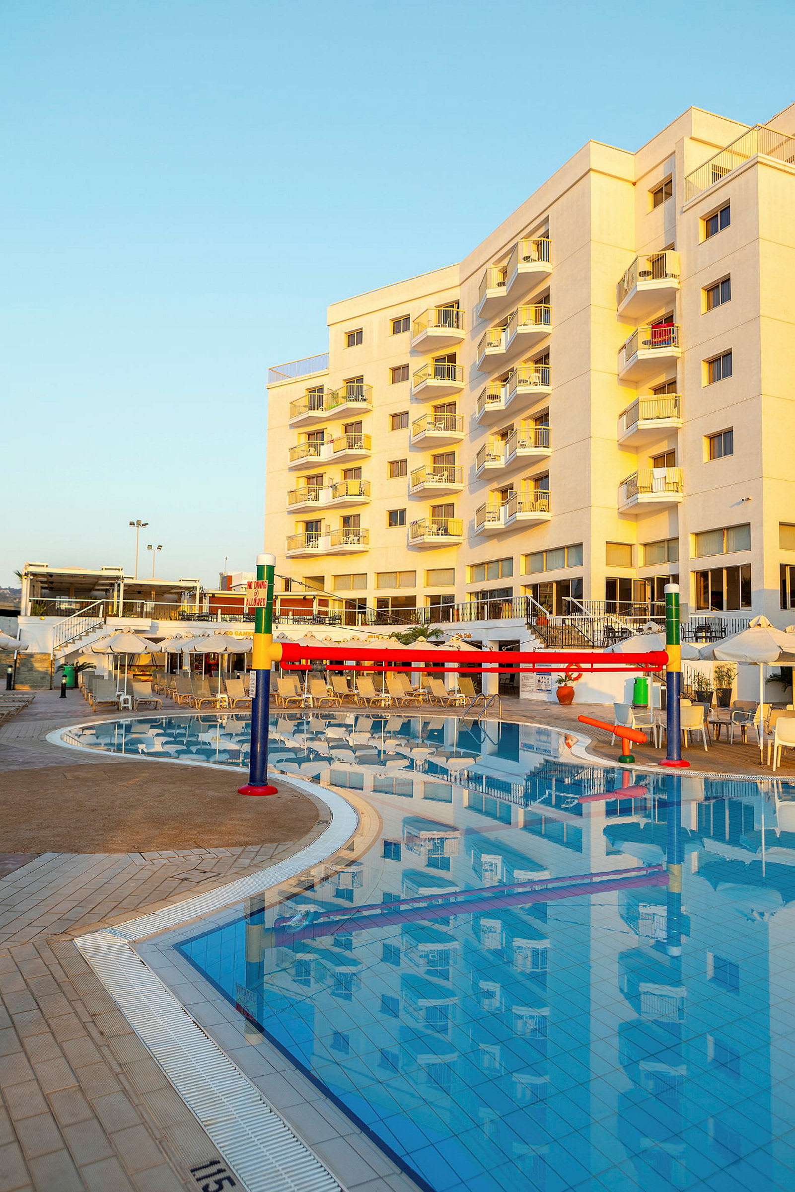 Stor byggnad med balkonger och en swimmingpool i förgrunden. (AI-genererad text)