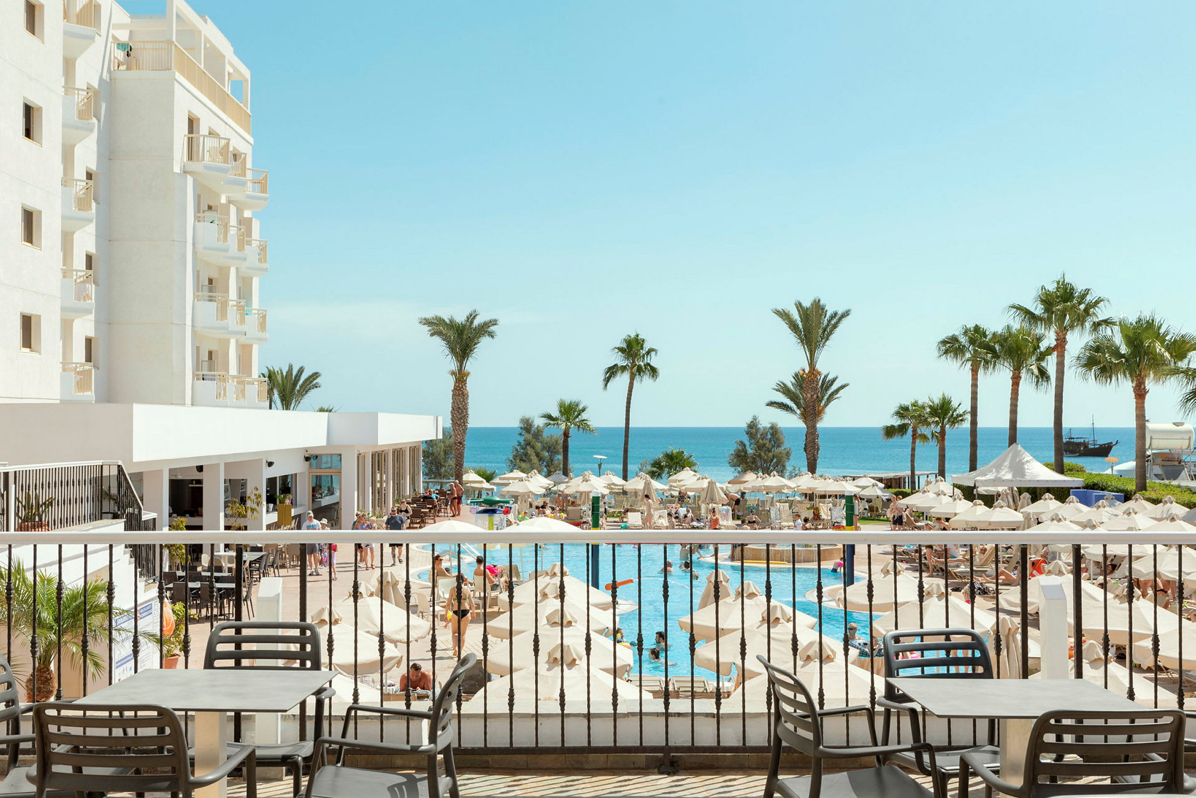 Hotellområde med pool, parasoller och havsutsikt. (AI-genererad text)