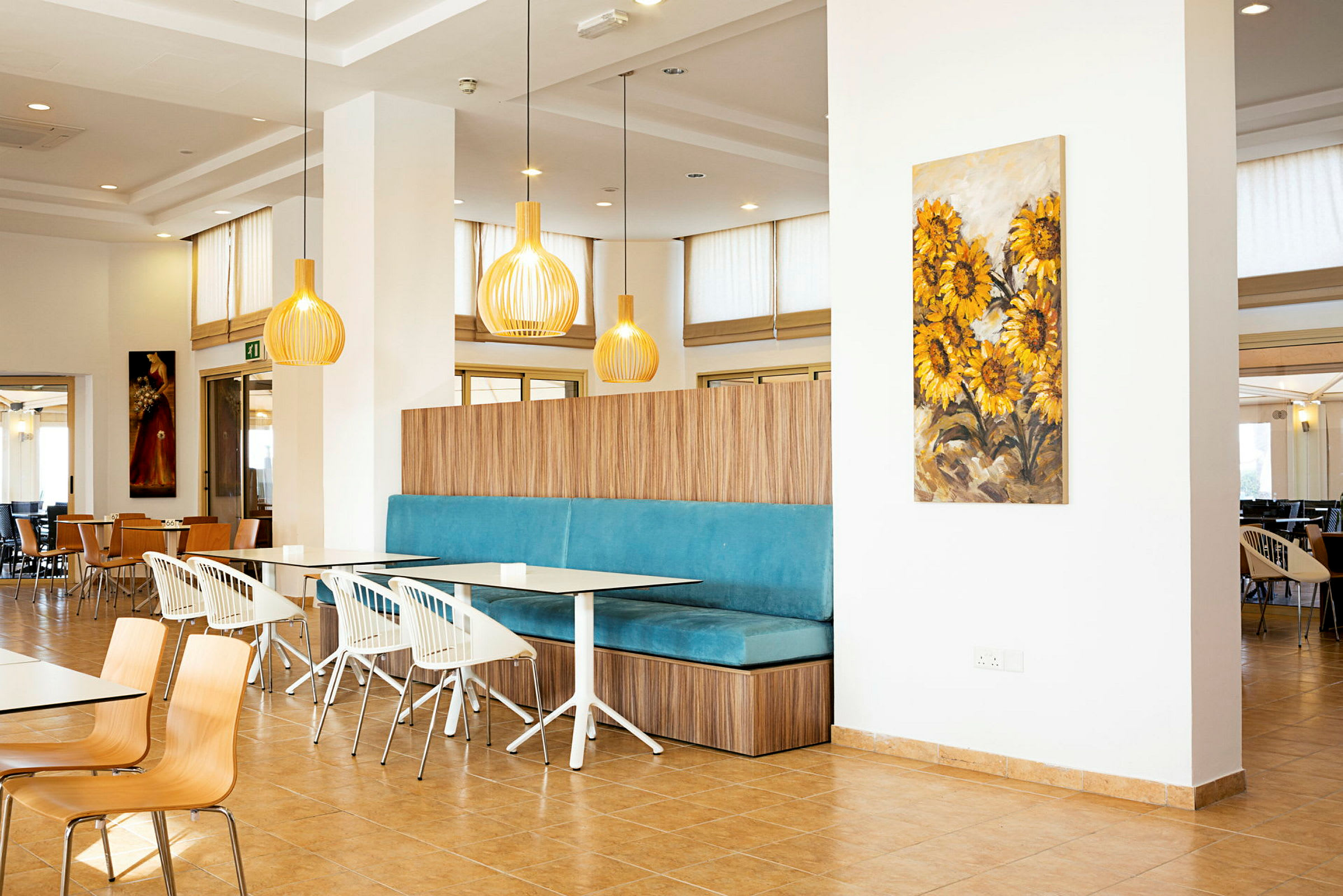 Interiör av en restaurang med modern inredning och färgstarkt väggkonstverk med solrosmotiv. (AI-genererad text)