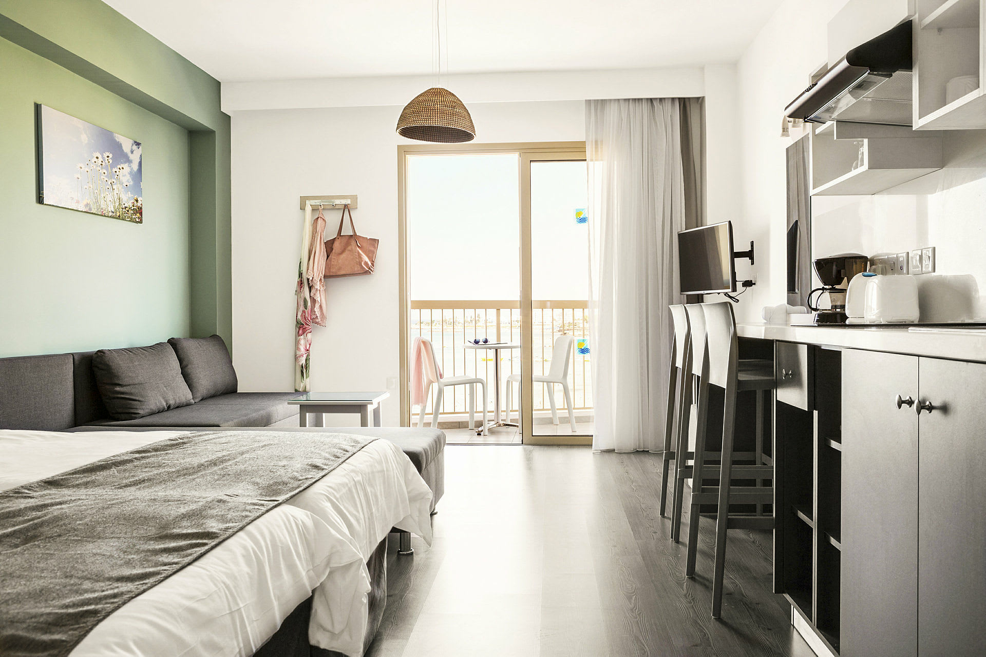 Ett modernt hotellrum med en bäddsoffa, säng, köksutrustning och balkong med utsikt. (AI-genererad text)