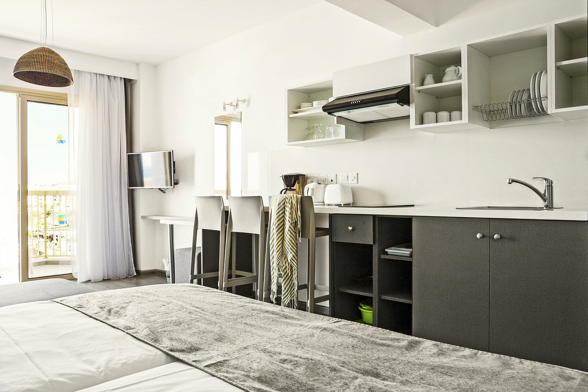 Ett hotellrum med ett köksutrymme, en säng och en balkong. (AI-genererad text)