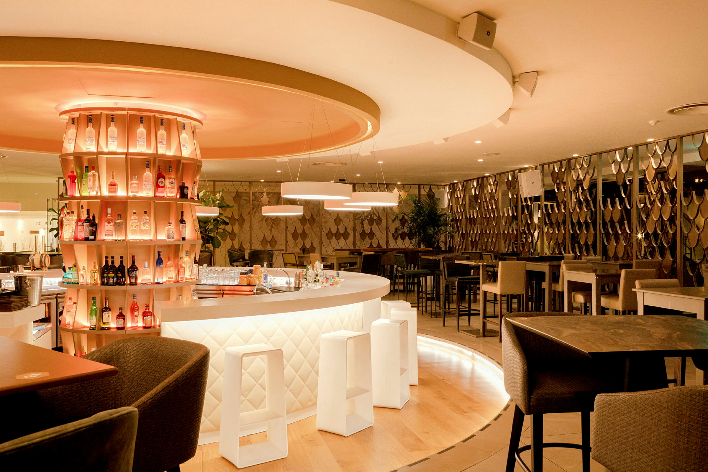 En stilren bar med belysta hyllor fyllda med flaskor och en modern inredning. (AI-genererad text)