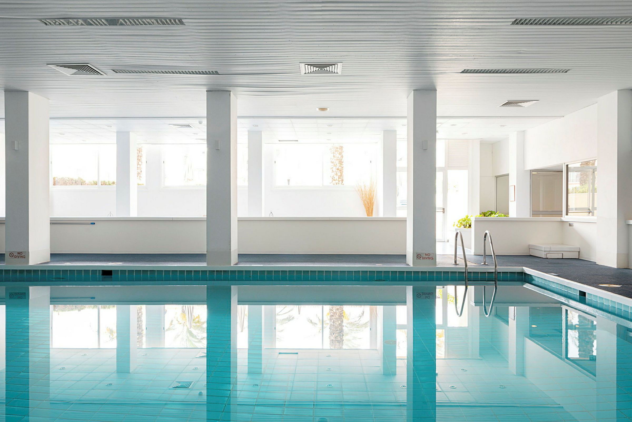 Inomhuspool med klart vatten och ljusa väggar. (AI-genererad text)