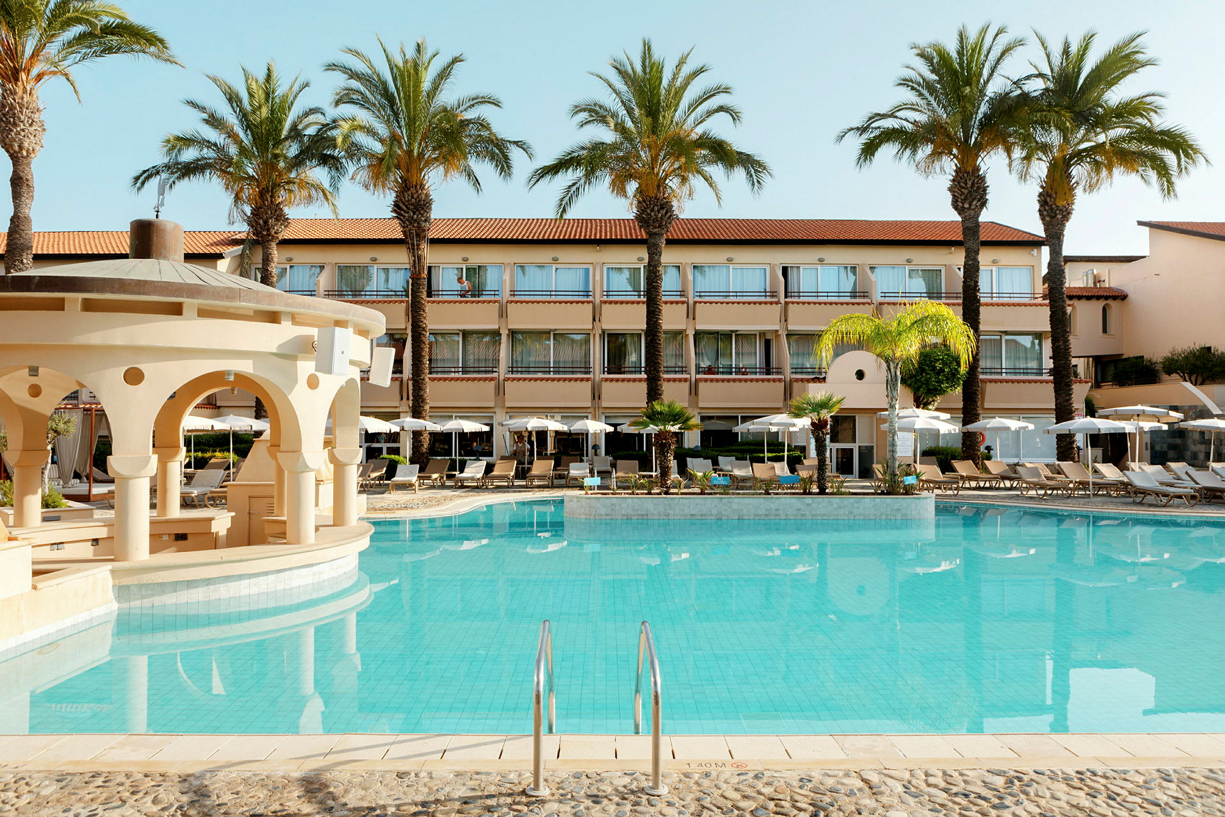 Bild av ett hotell med utomhuspool och omgivande solstolar och parasoller. (AI-genererad text)