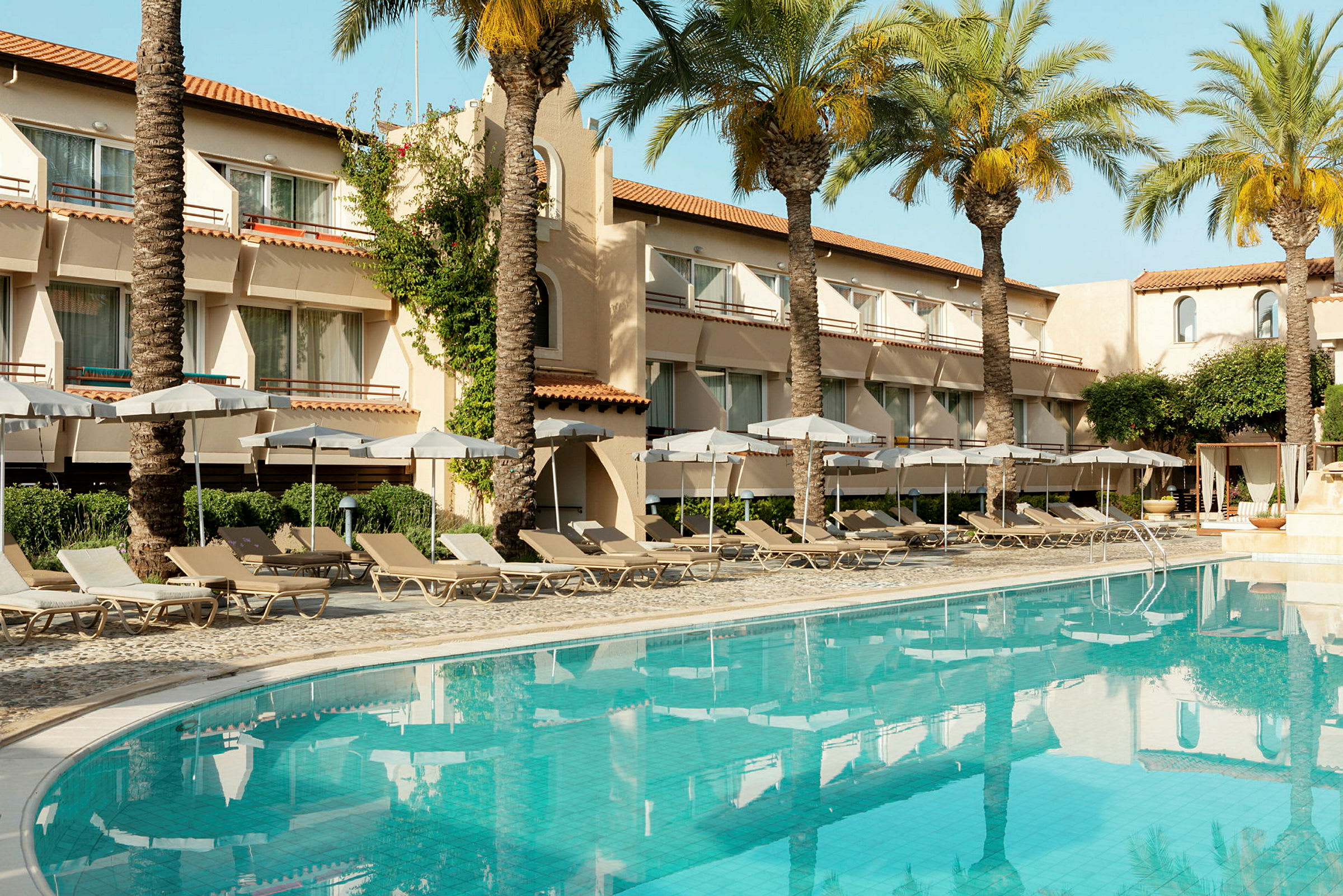 Ett hotell med balkonger, palmer och en pool. (AI-genererad text)