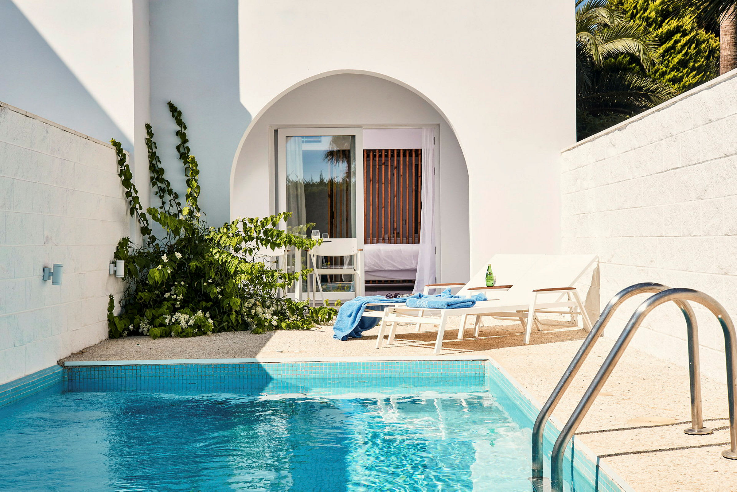 Privat terrass med pool, två solstolar och tillhörande hotellrum syns. (AI-genererad text)
