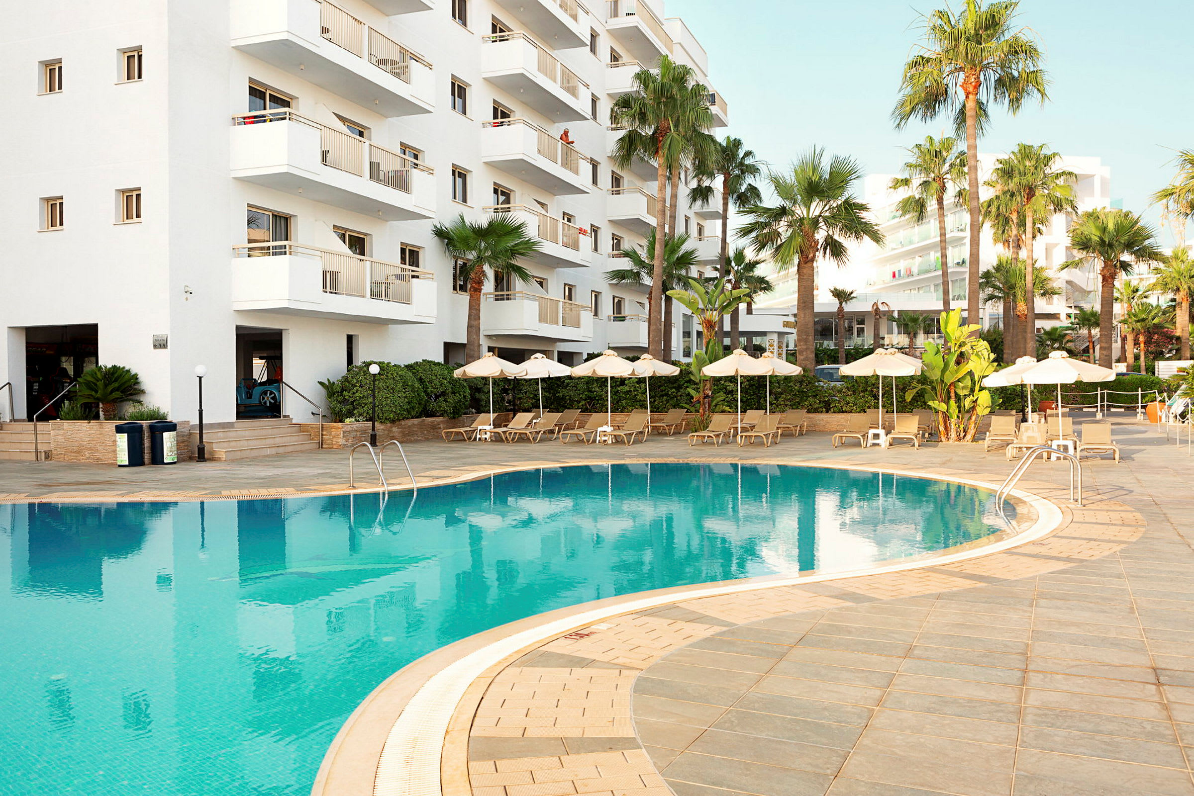 Utomhuspool vid hotell med vit fasad. (AI-genererad text)