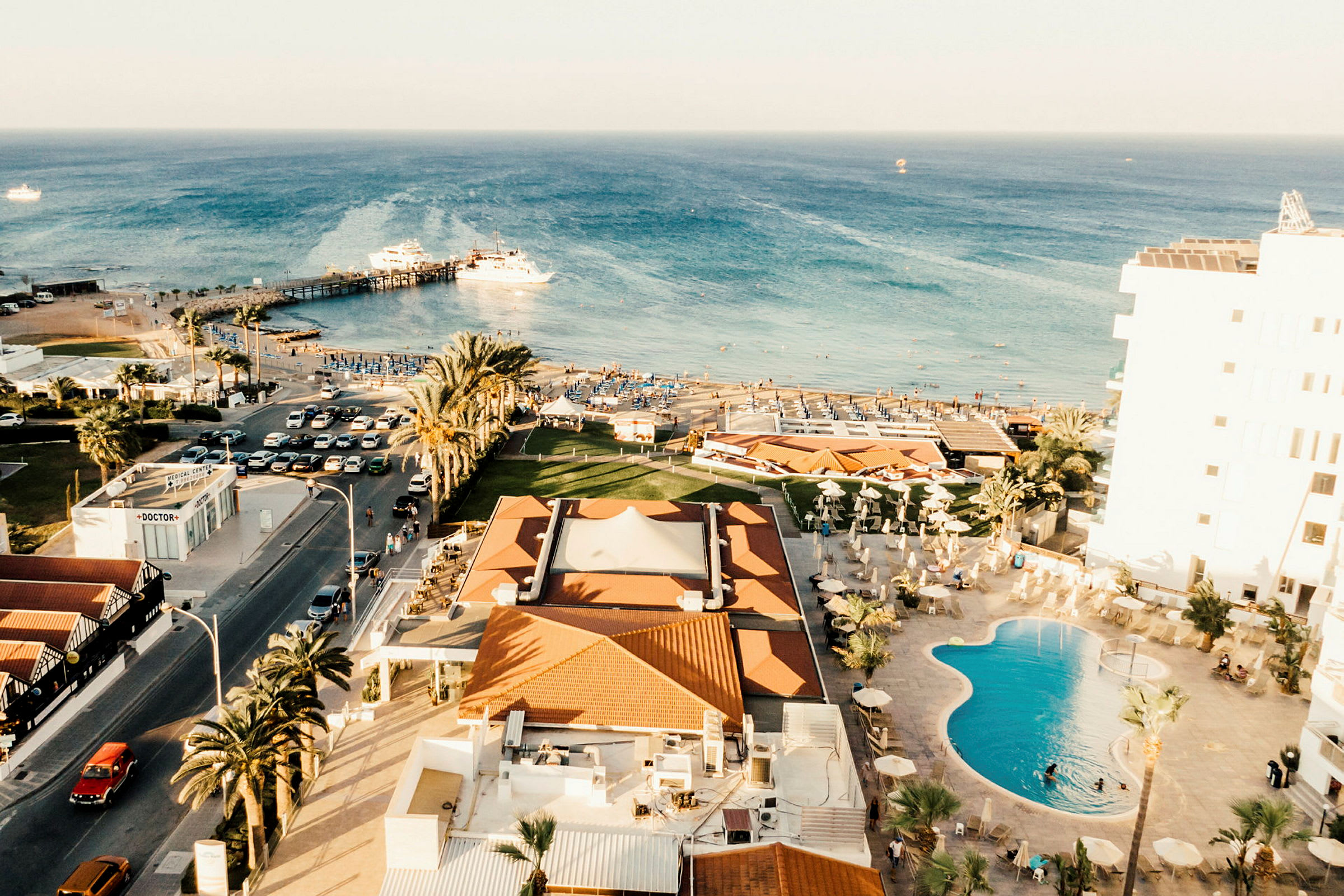 Utsikt över kust med hotell, pool, palmer och strand som leder ut till havet. (AI-genererad text)