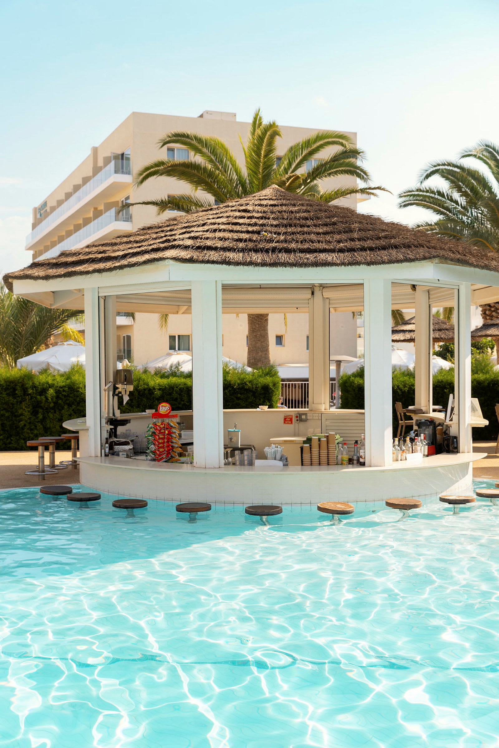 En poolbar med sittplatser i vattnet, omgiven av palmer. (AI-genererad text)