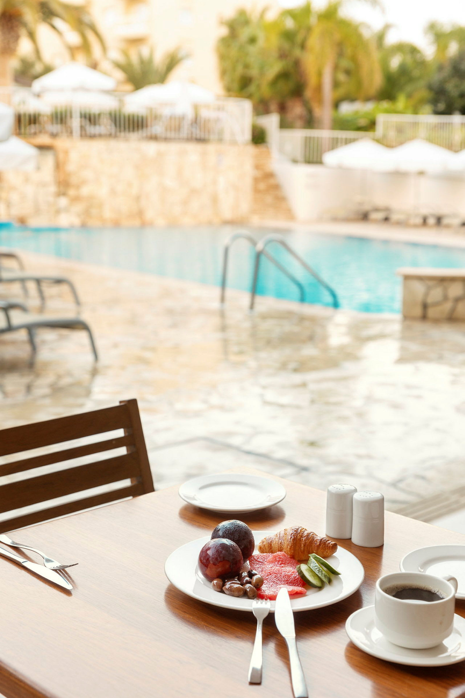 Frukost med kaffe och frukt vid en pool. (AI-genererad text)