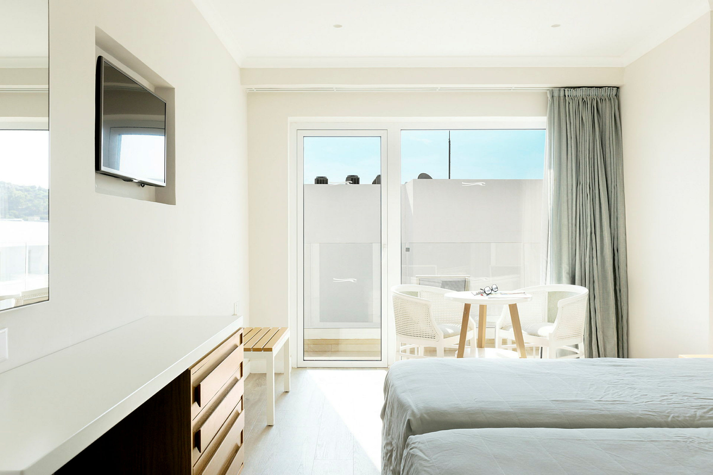Hotellrum med ljusa möbler, sängar och ett bord nära ett stort fönster. (AI-genererad text)