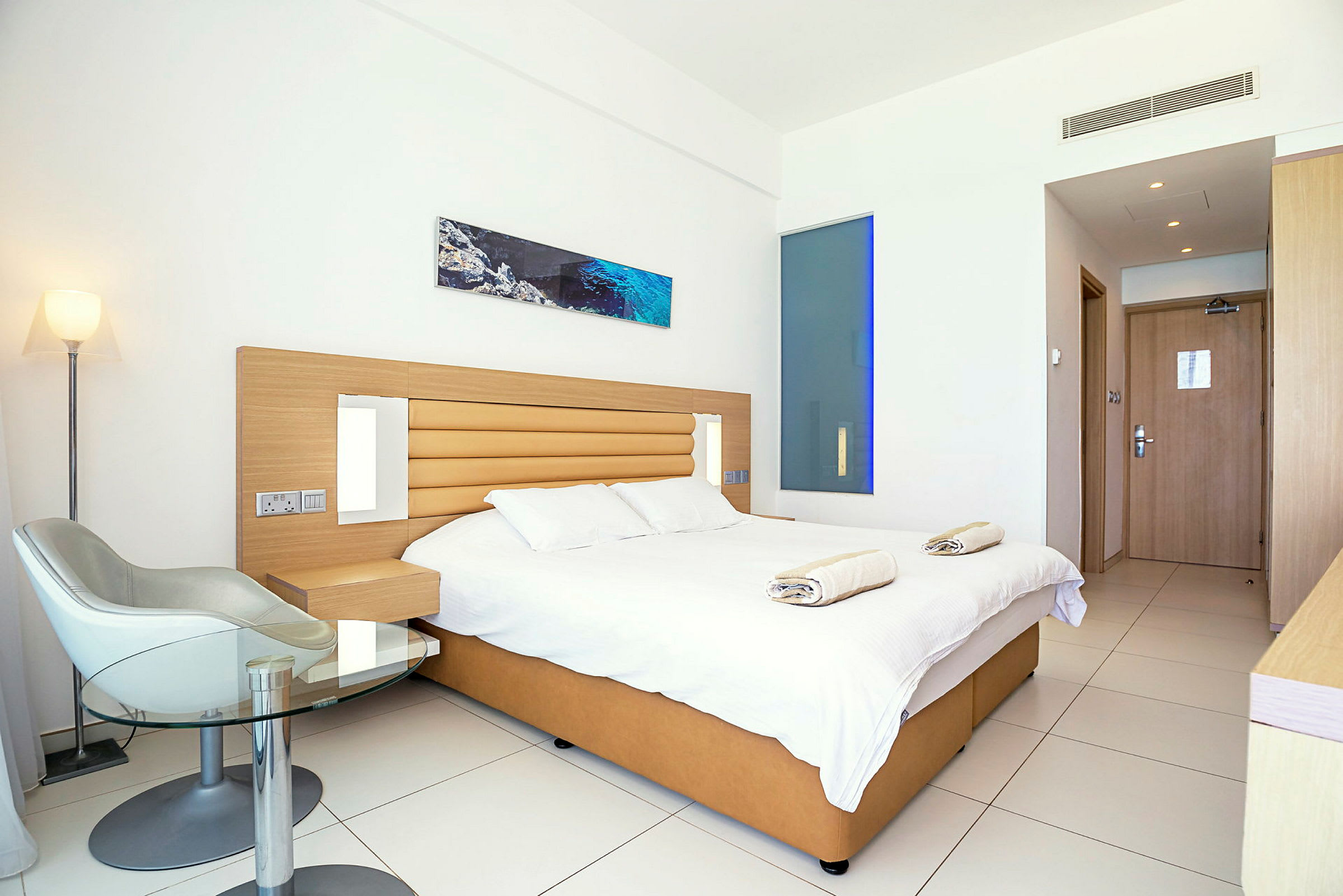 Modernt hotellrum med dubbelsäng, stol och bord. (AI-genererad text)