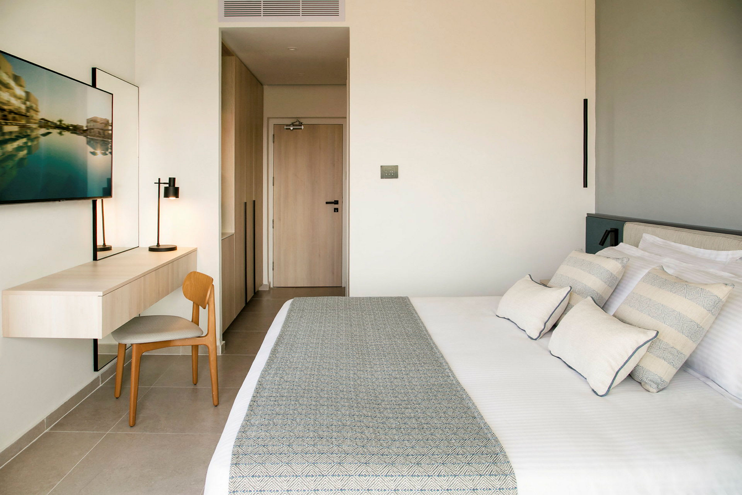 Modernt hotellrum med säng, skrivbord, stol och TV. (AI-genererad text)