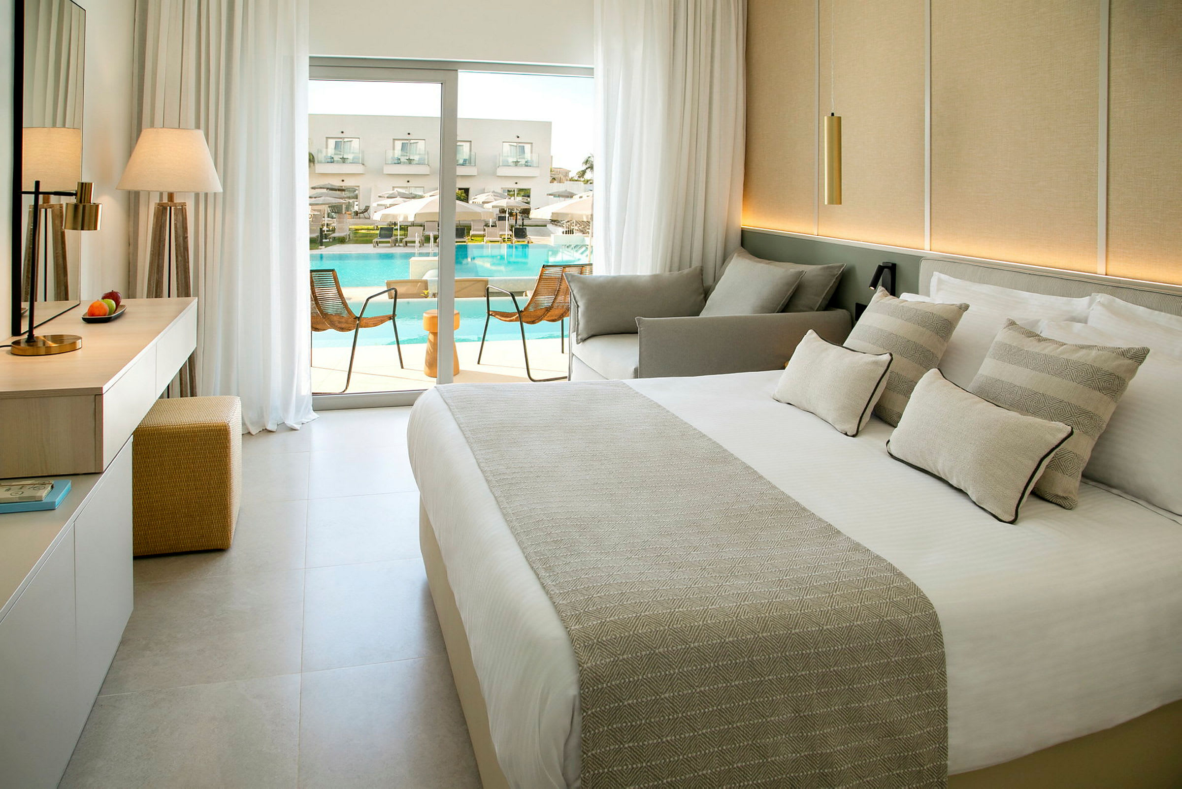 Ett hotellrum med modern inredning och balkong med utsikt över en pool. (AI-genererad text)