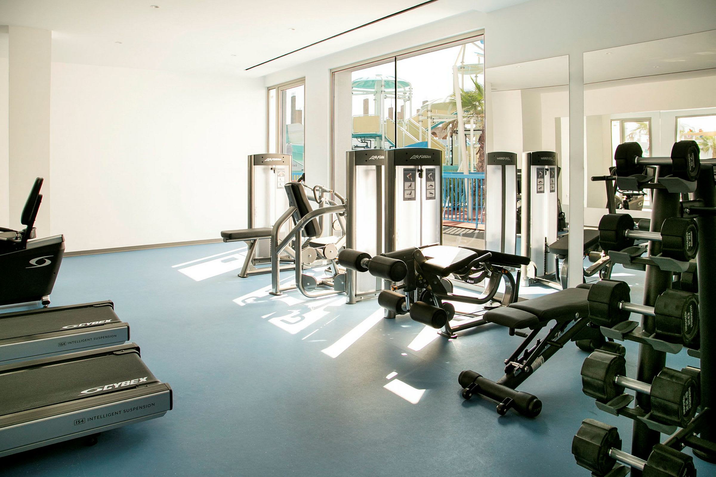 Ett gym med träningsmaskiner och hantlar åtskilda på golvet. (AI-genererad text)