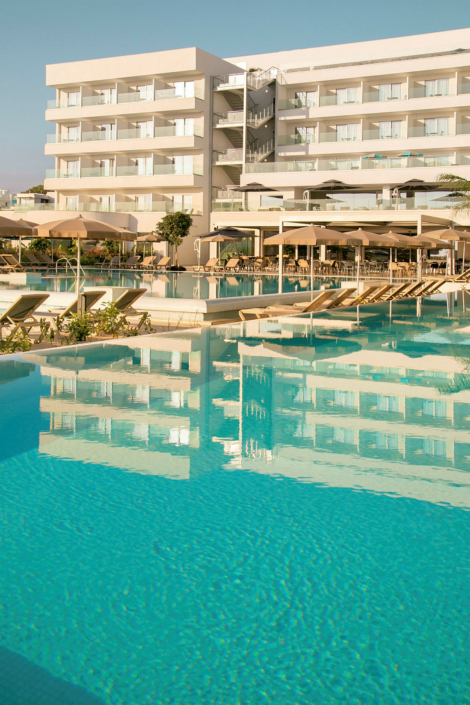 Hotell med poolområde som reflekteras i vattnet. (AI-genererad text)