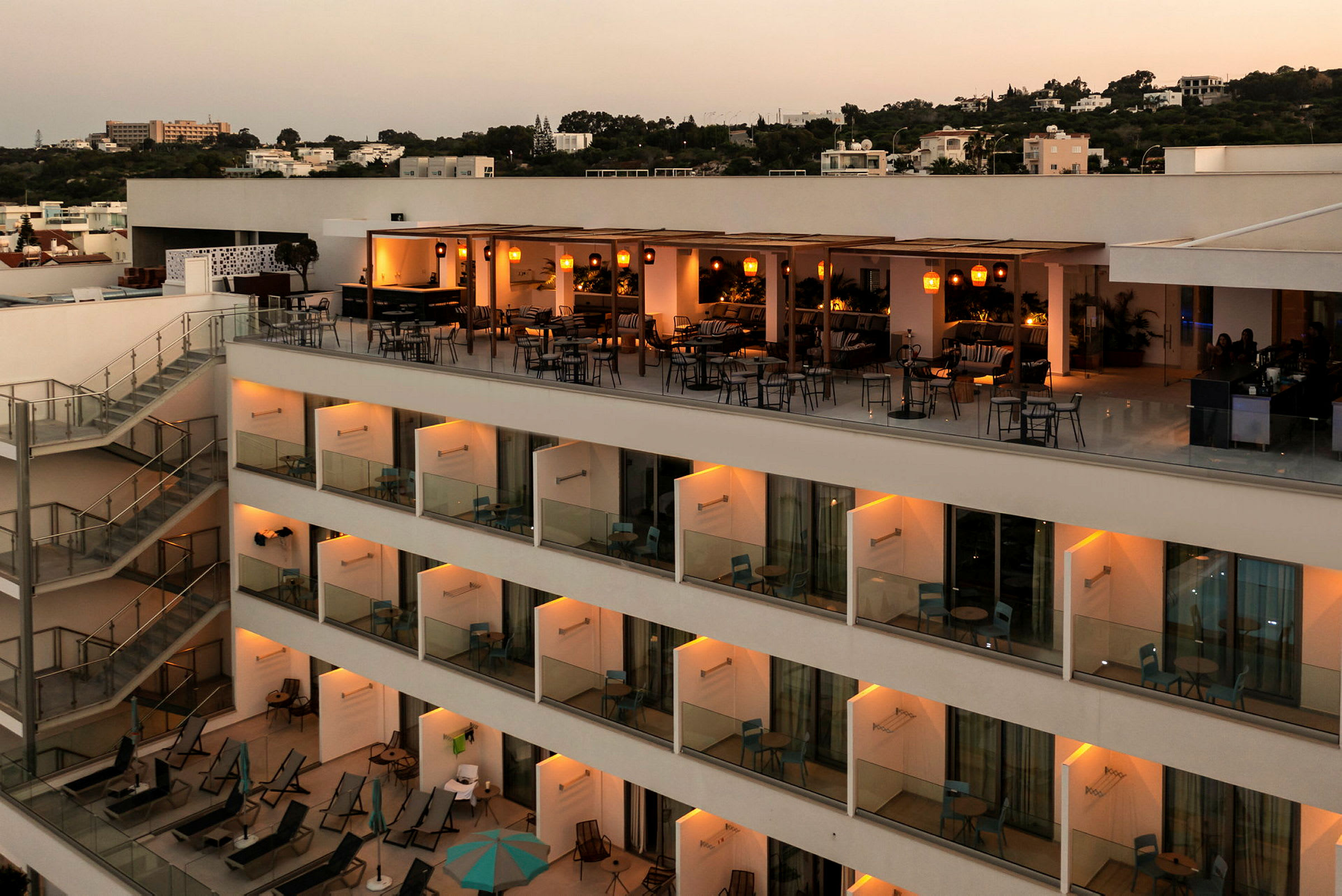 En hotellbyggnad med en upplyst terrass och balkonger. (AI-genererad text)