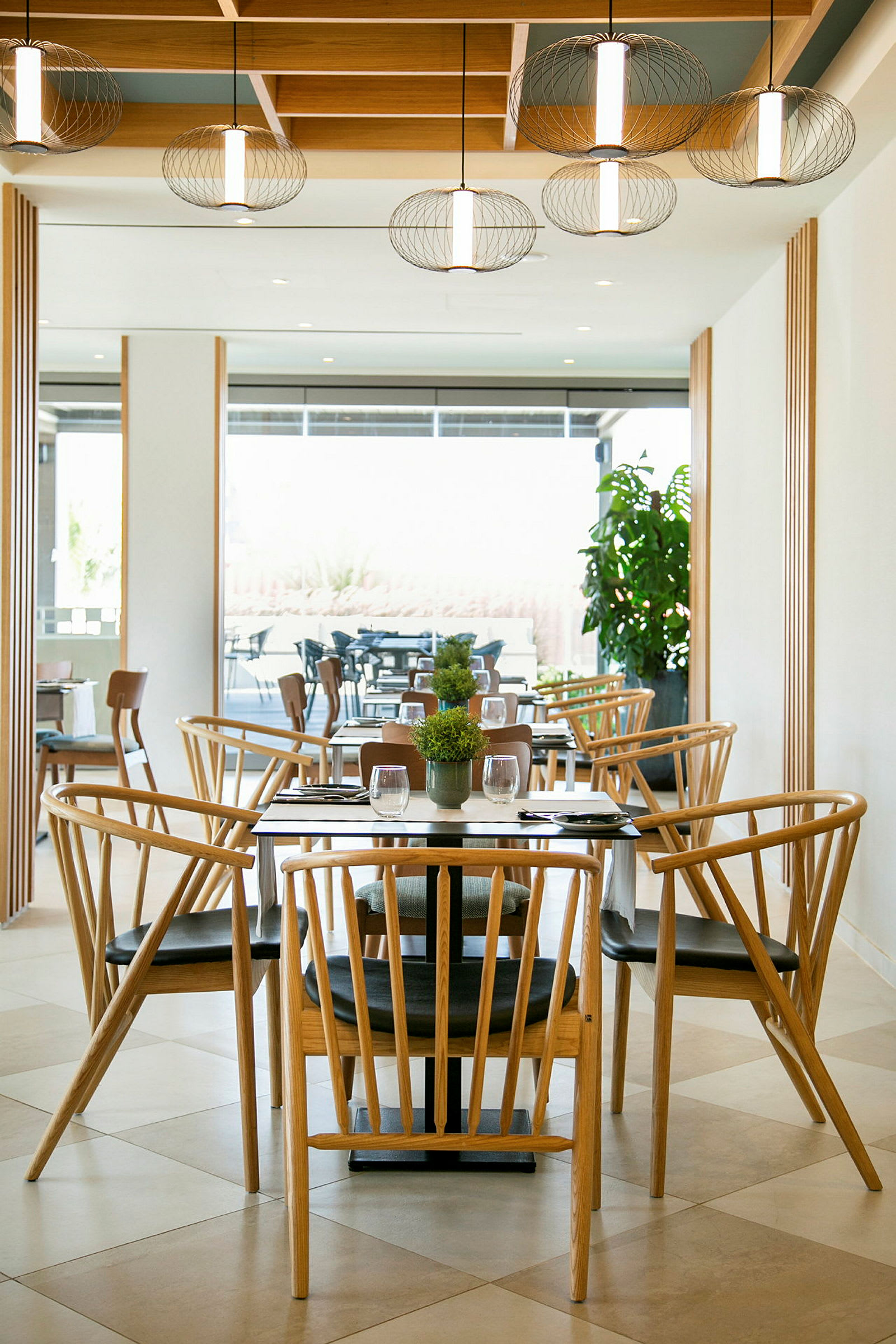En restaurang med trästolar och bord samt dekorativa lampor i taket. (AI-genererad text)