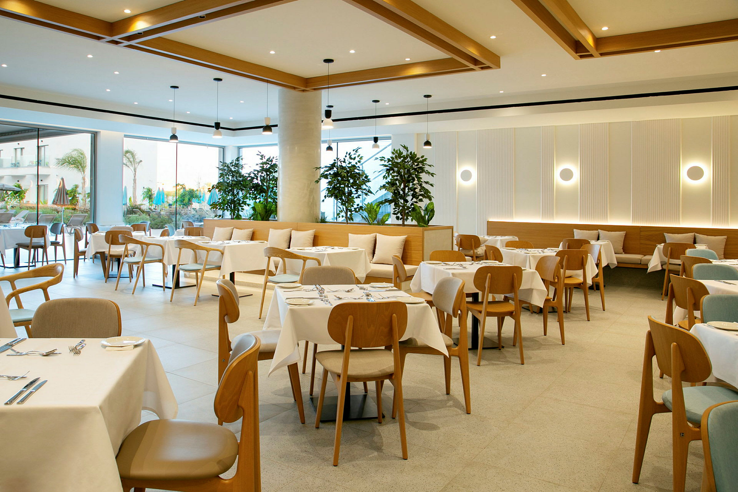 En modern restaurang med dukade bord och trästolar, samt växter som dekoration. (AI-genererad text)