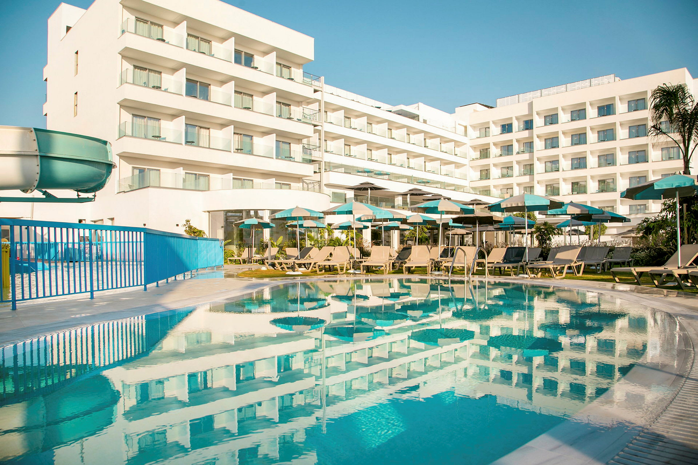 Hotellbyggnad med balkonger och en swimmingpool i förgrunden. (AI-genererad text)