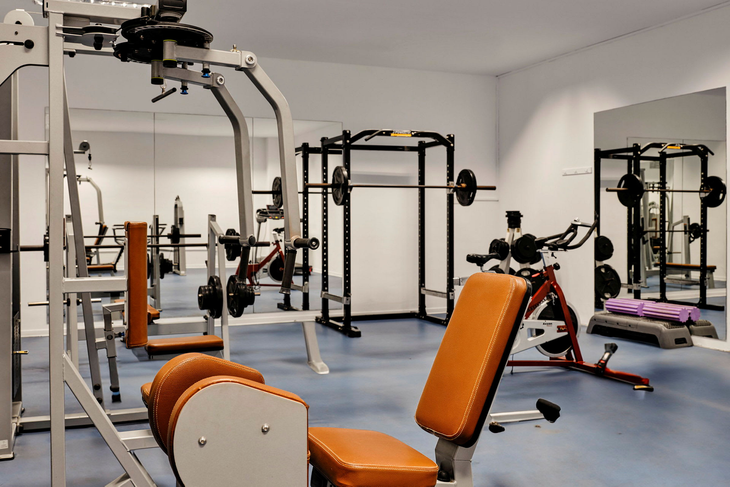 Bild på ett gym med träningsmaskiner och speglar. (AI-genererad text)